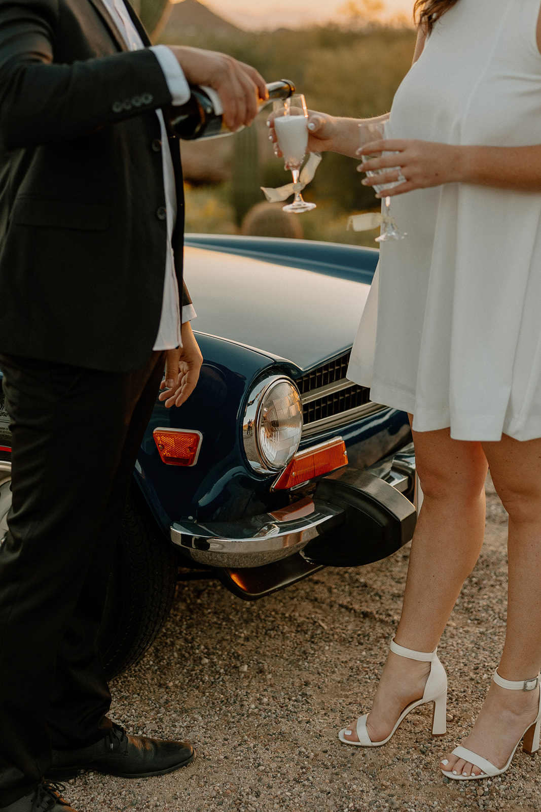 stunning couple pose with a vintage car during their engagement photos in the Arizona dessert