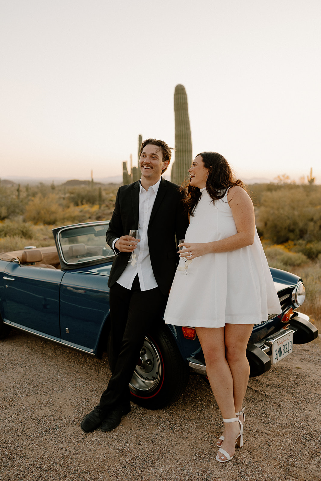 stunning couple pose with a vintage car during their engagement photos in the Arizona dessert