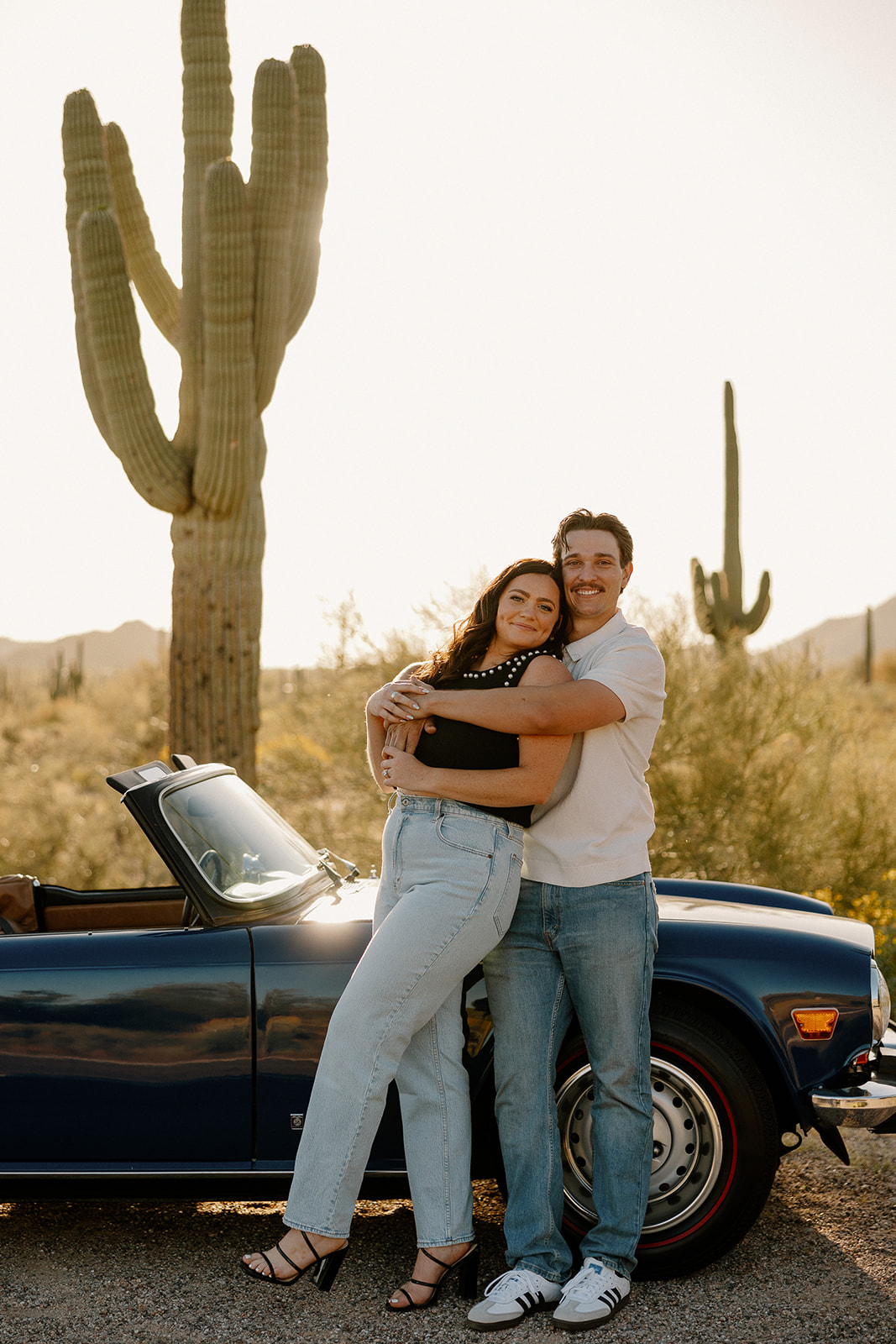 stunning couple pose with a vintage car during their engagement photos in the Arizona dessert