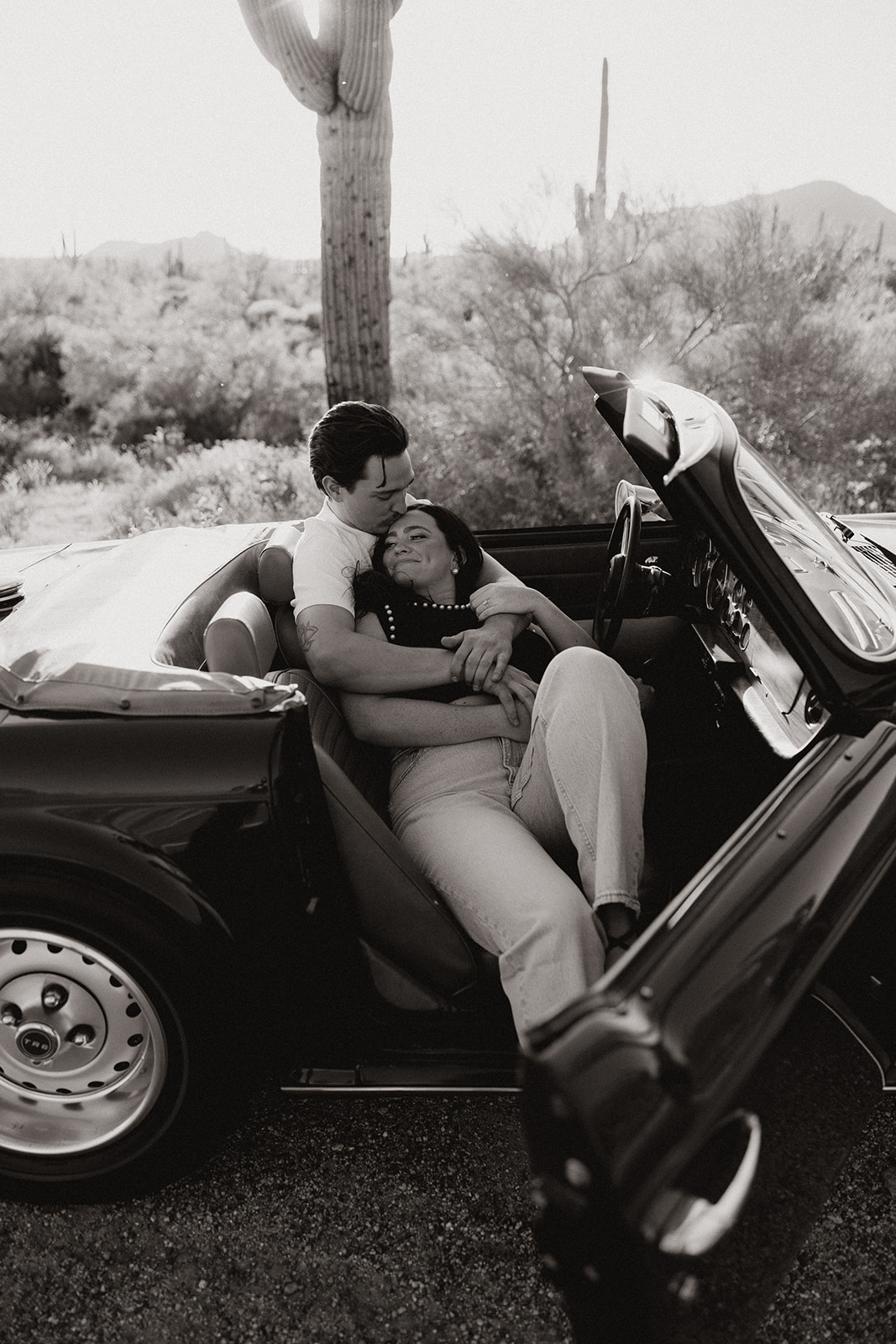 stunning couple pose with a vintage car during their engagement photos in the Arizona dessert