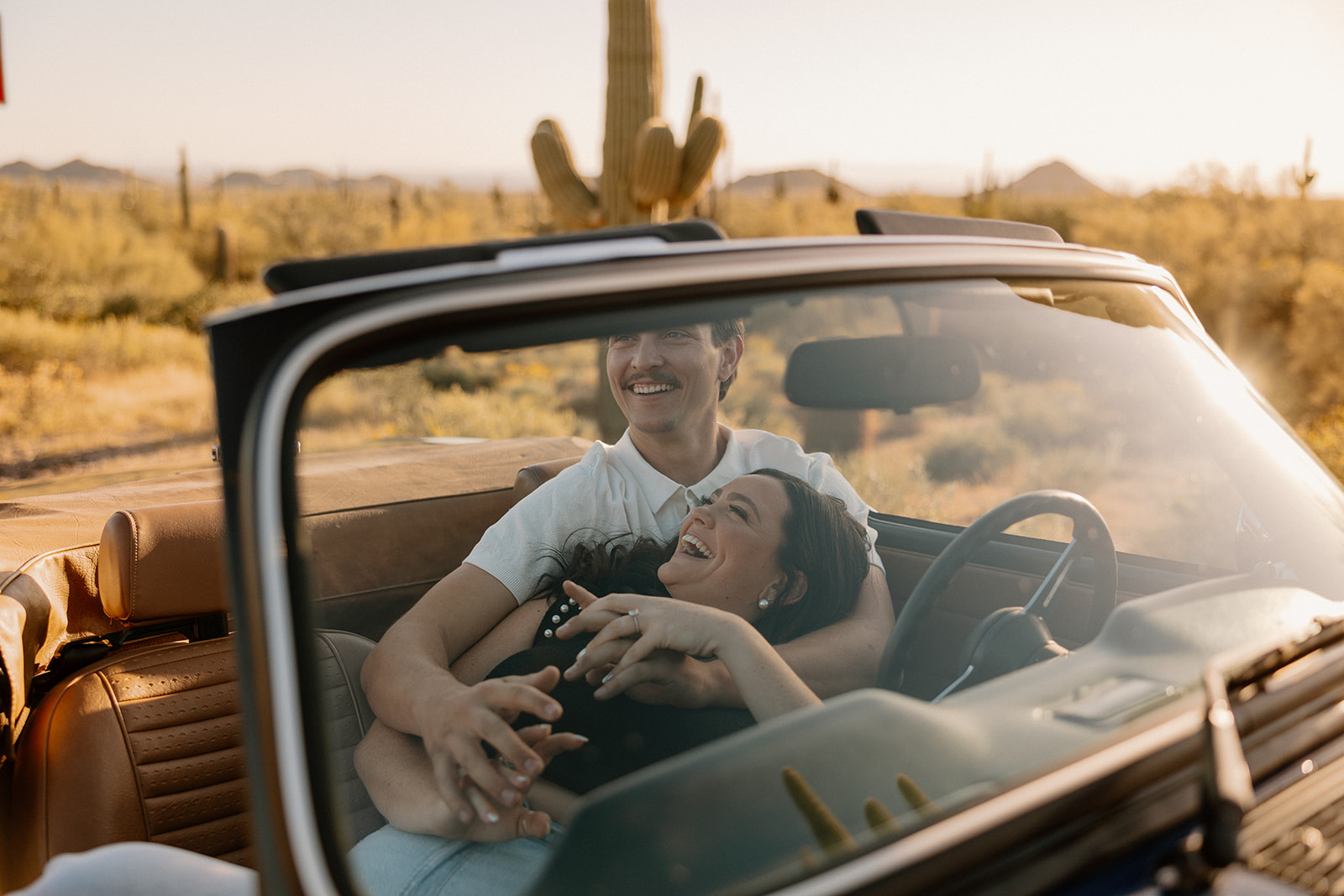 stunning couple pose with a vintage car during their engagement photos in the Arizona dessert