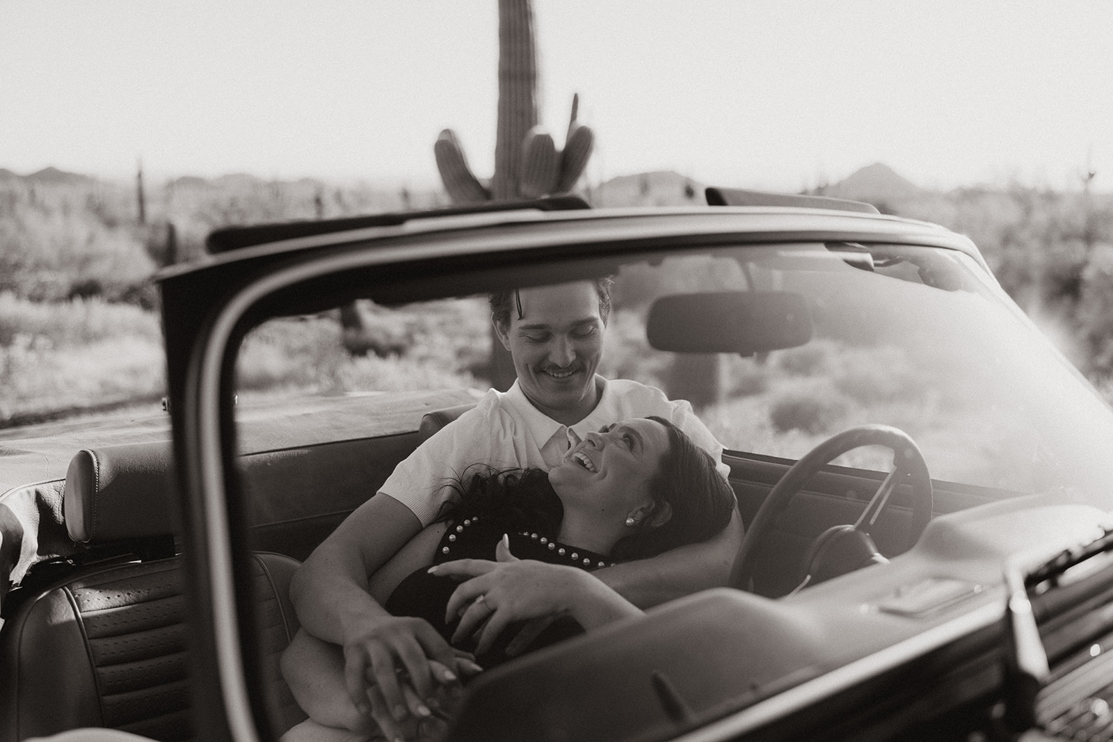 stunning couple pose with a vintage car during their engagement photos in the Arizona dessert