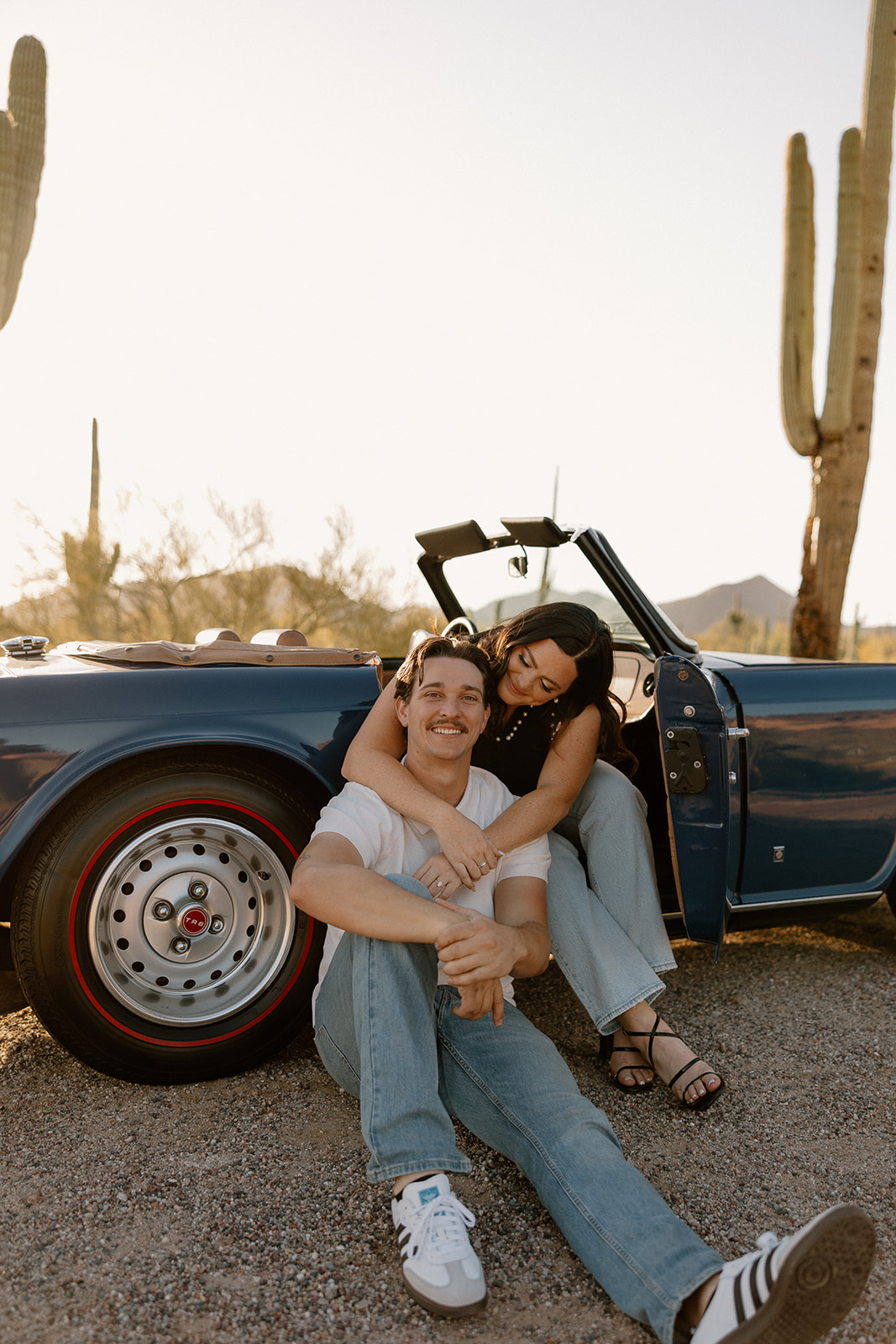 stunning couple pose with a vintage car during their engagement photos in the Arizona dessert