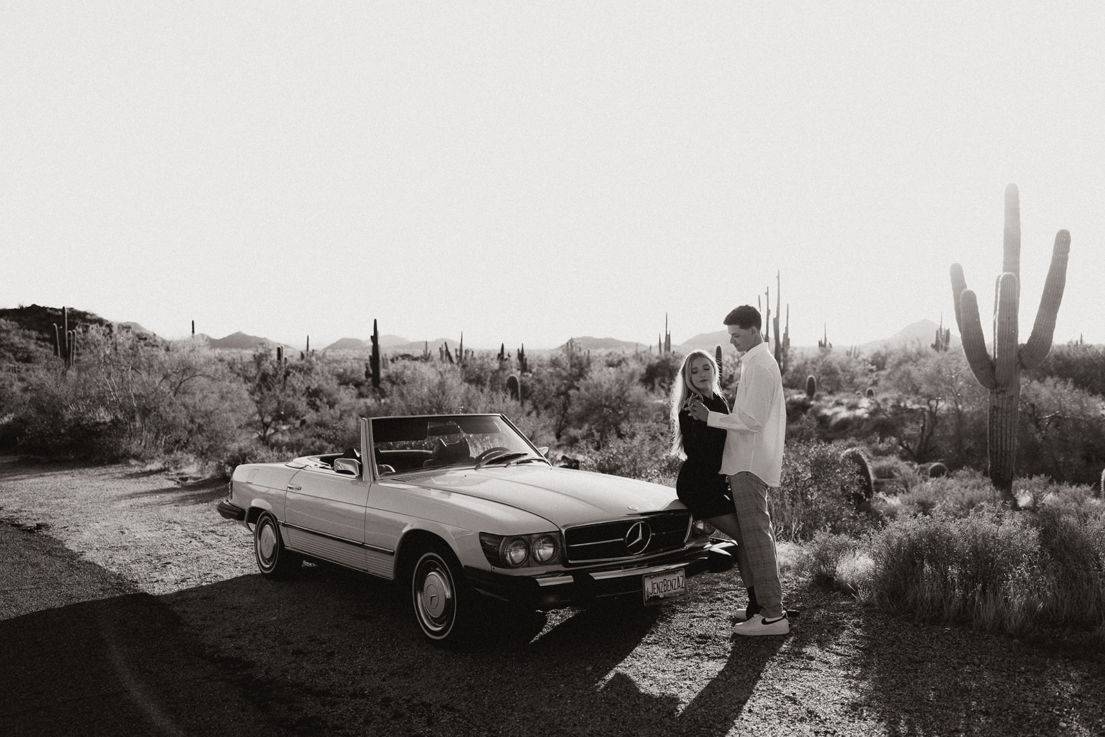 stunning couple pose with a vintage car during their engagement photos in the Arizona dessert