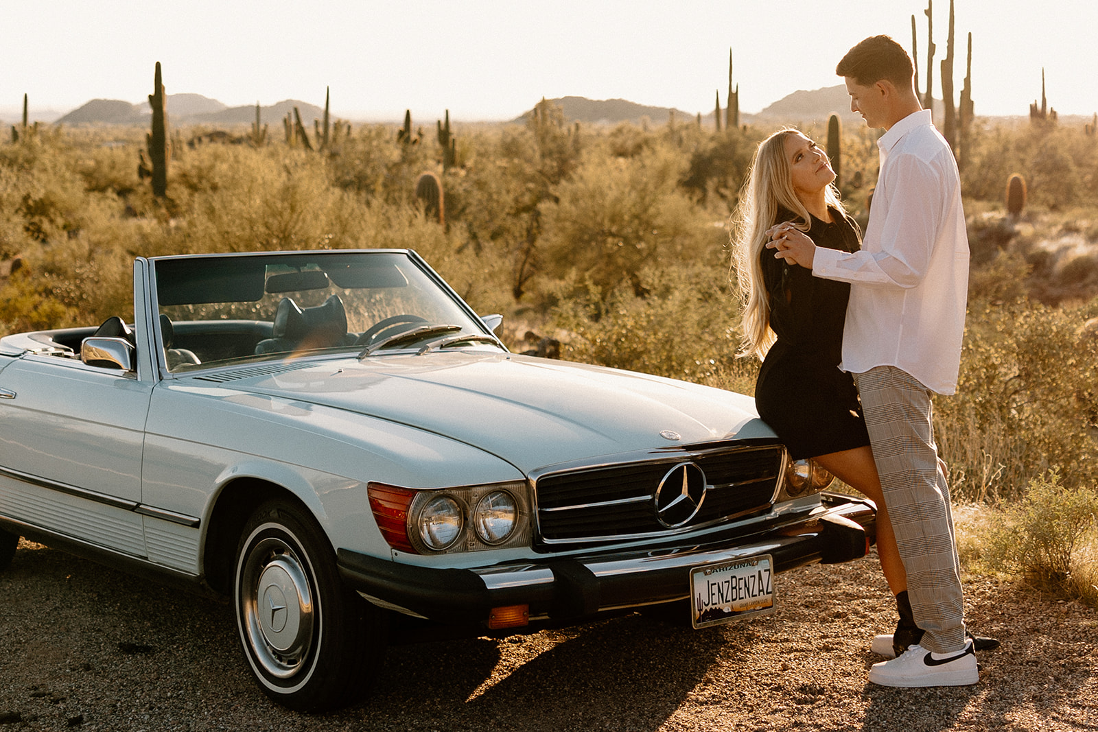 stunning couple pose with a vintage car during their engagement photos in the Arizona dessert