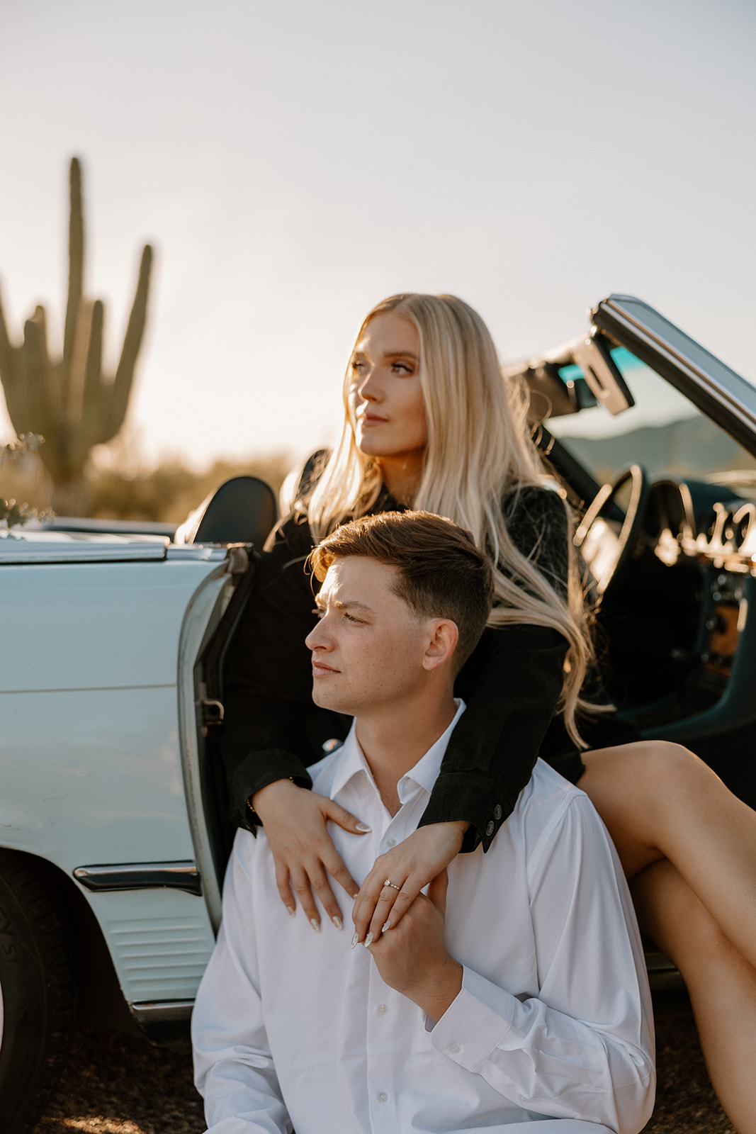 stunning couple pose with a vintage car during their engagement photos in the Arizona dessert