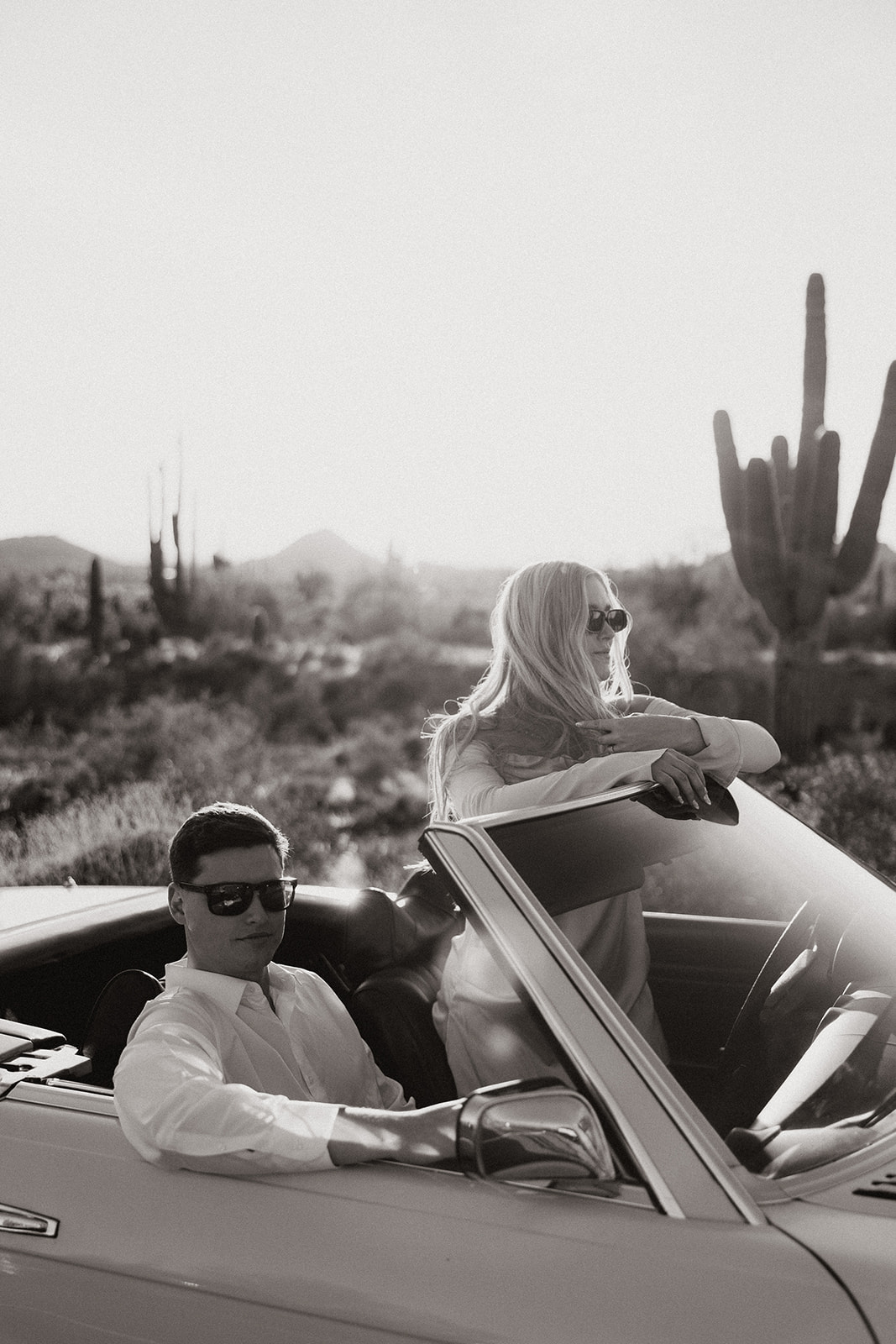 stunning couple pose with a vintage car during their engagement photos in the Arizona dessert