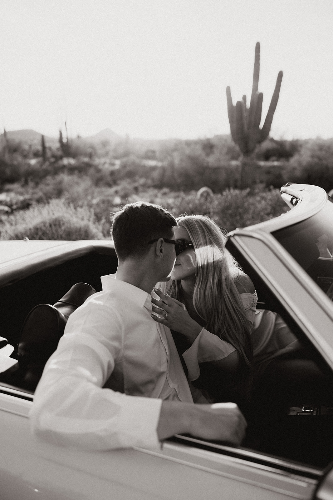 stunning couple pose with a vintage car during their engagement photos in the Arizona dessert