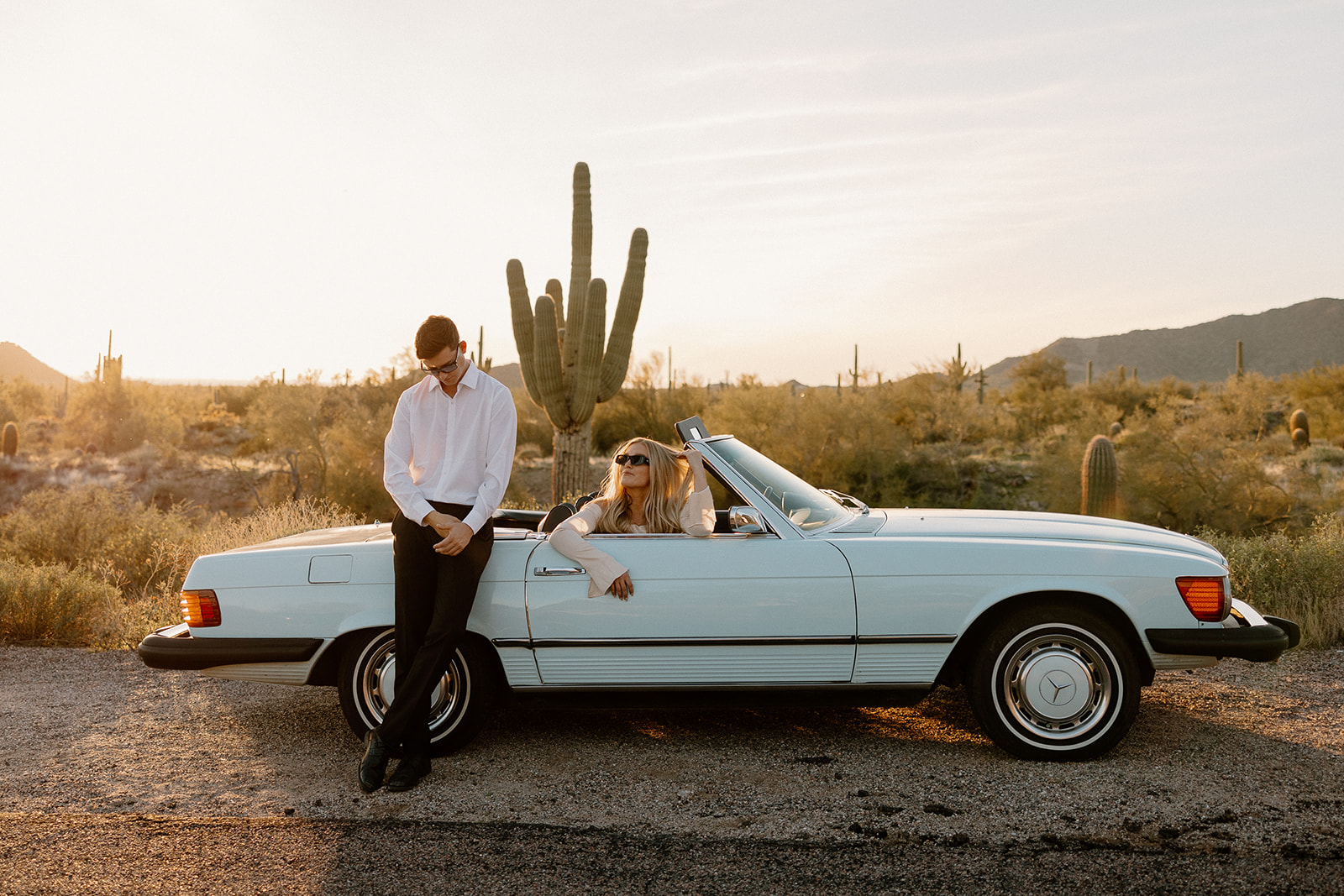 stunning couple pose with a vintage car during their engagement photos in the Arizona dessert