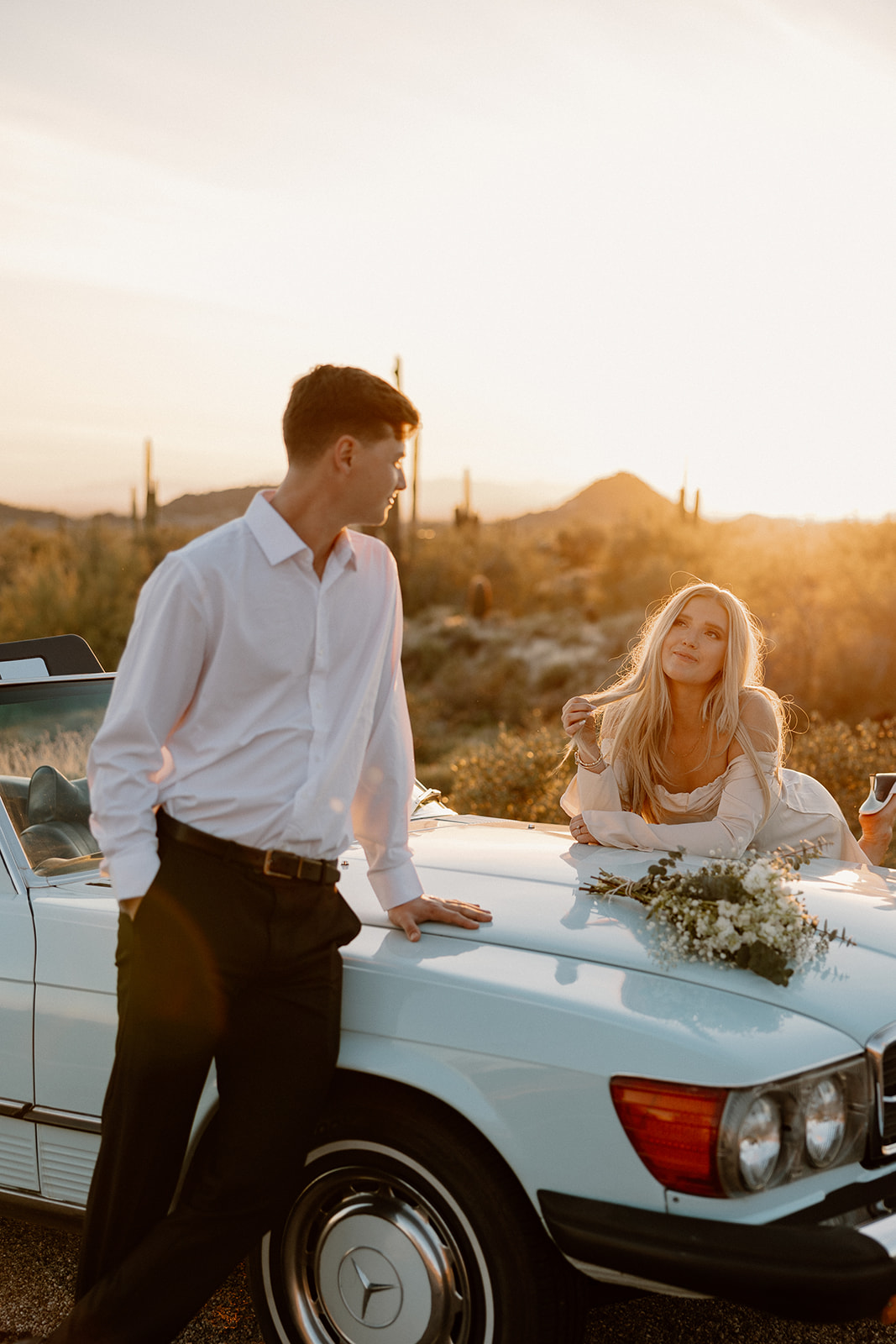 stunning couple pose with a vintage car during their engagement photos in the Arizona dessert