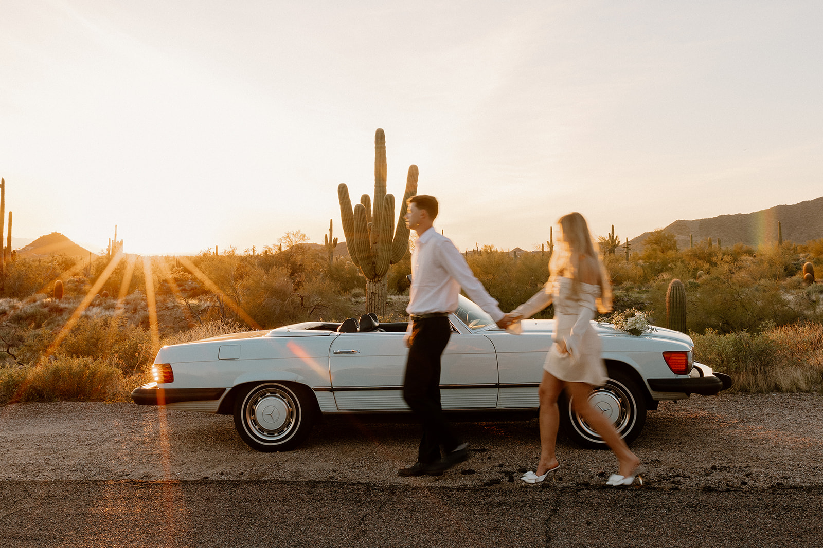 stunning couple pose with a vintage car during their engagement photos in the Arizona dessert