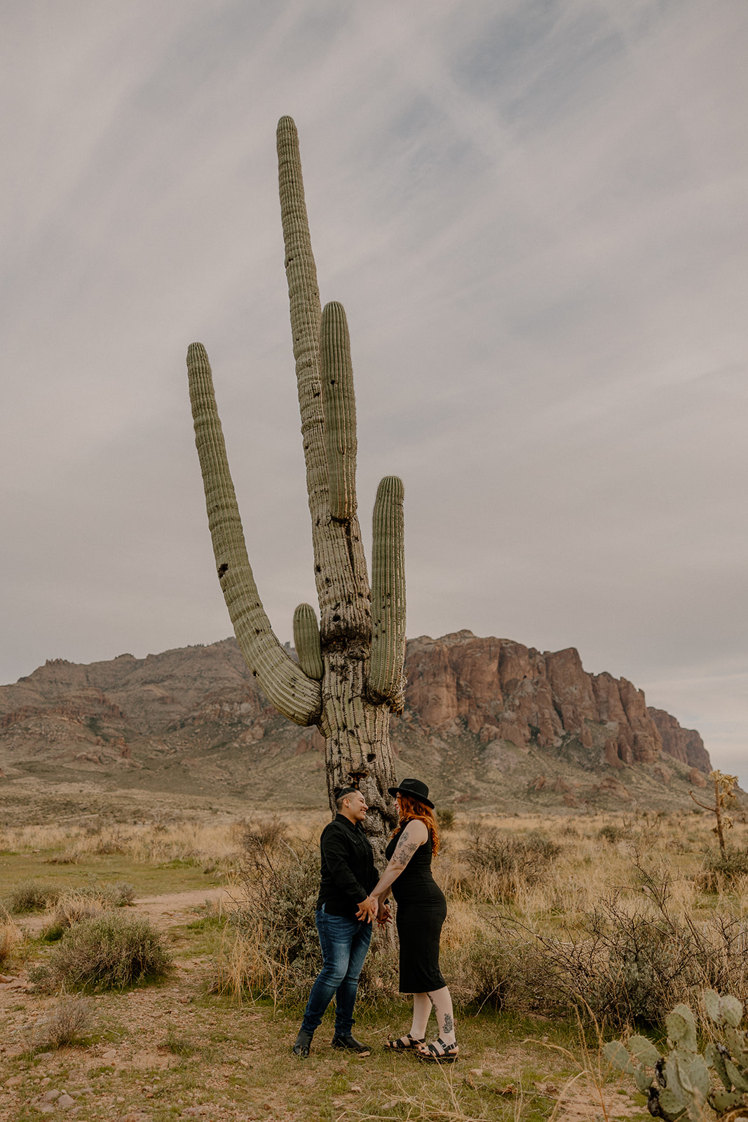 same sex couple pose together during their engagement photos at superstition mountain