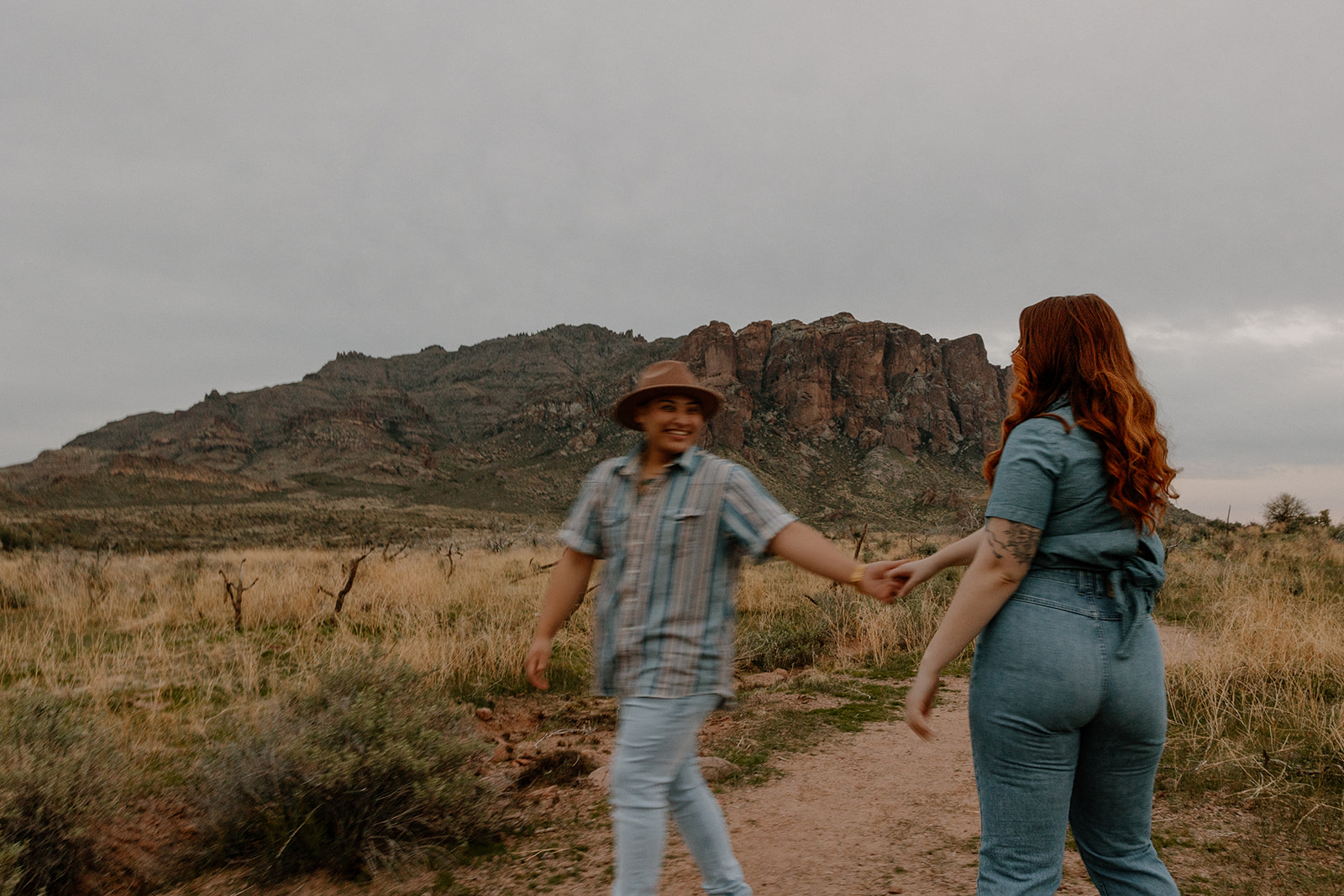 same sex couple pose together during their engagement photos at superstition mountain