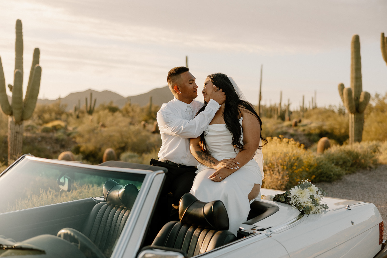 stunning couple pose with a vintage car during their engagement photos in the Arizona dessert