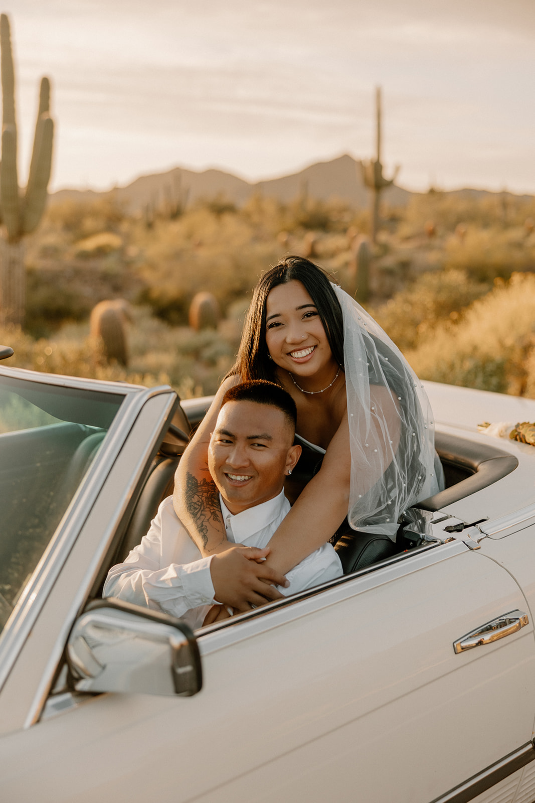 stunning couple pose with a vintage car during their engagement photos in the Arizona dessert