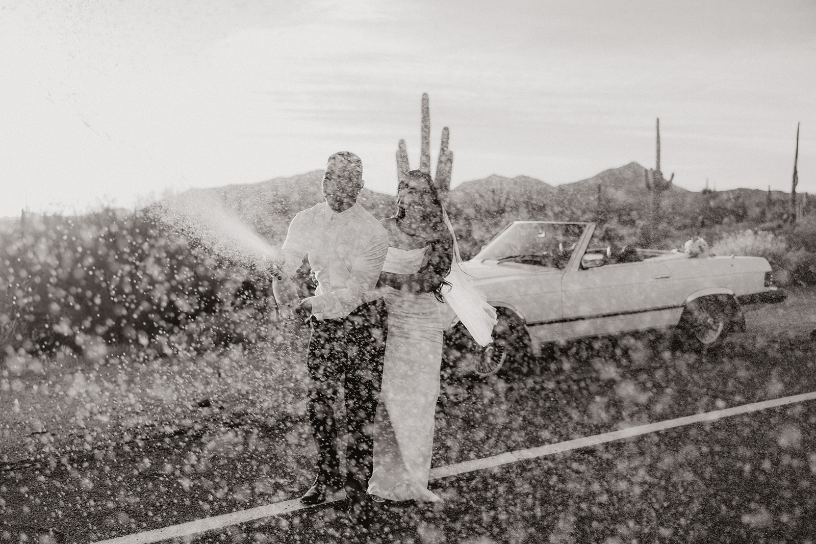 stunning couple pose with a vintage car during their engagement photos in the Arizona dessert