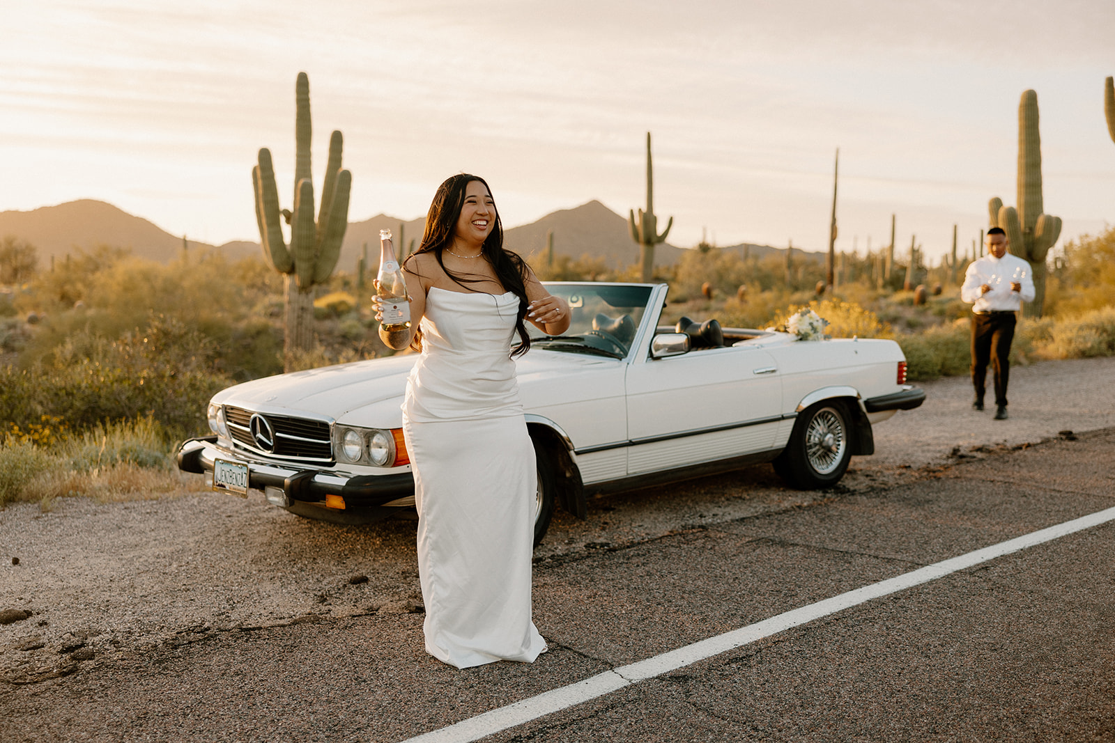 stunning couple pose with a vintage car during their engagement photos in the Arizona dessert