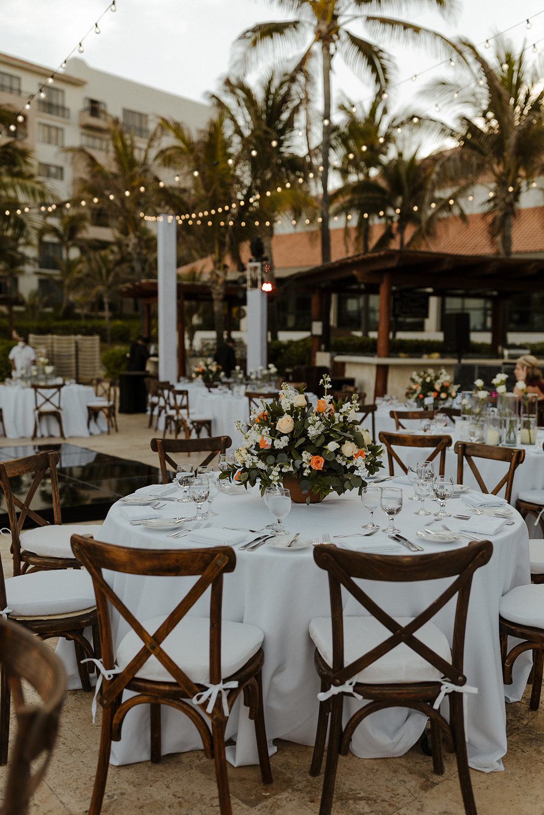 white table linens decorated with orange, yellow, and pink florals with string lights