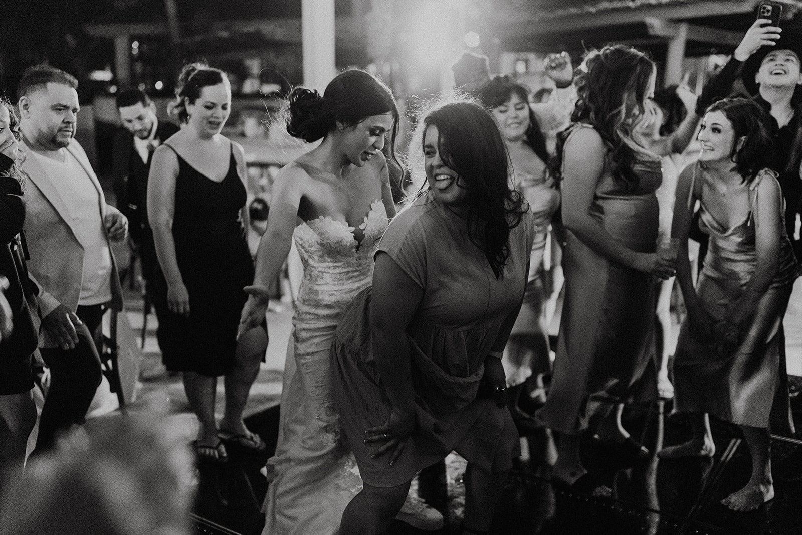 bride in white lacy dress dancing with bridesmaids in chrome dresses