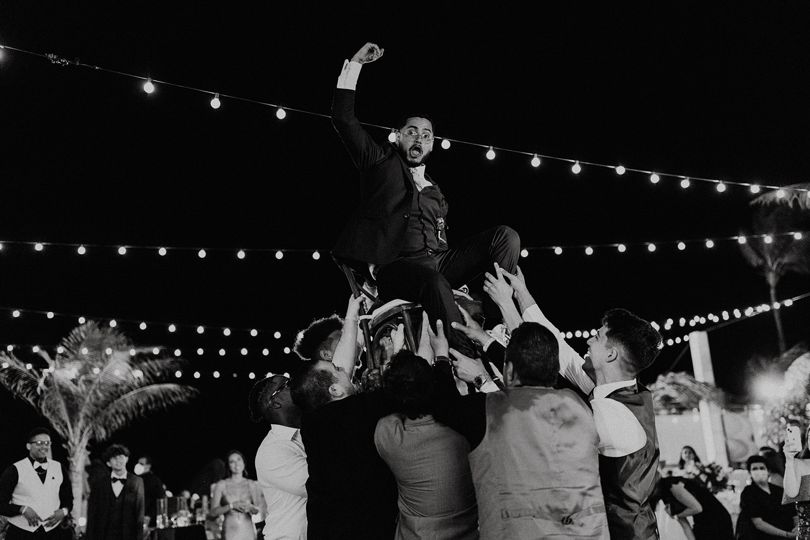 groom is held up in the air by groomsmen during wedding reception 