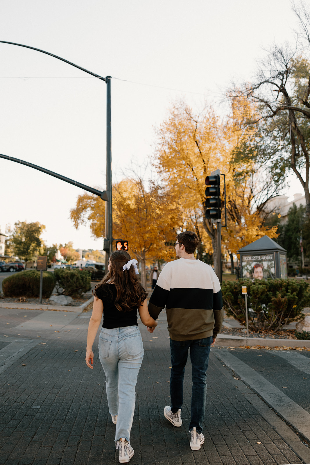 couple holding each other during the fall season with orange and yellow leaves on the ground