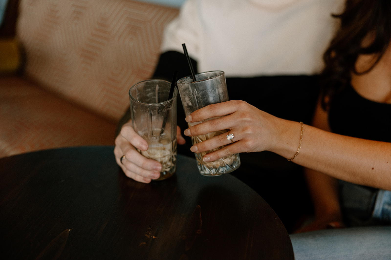 couple sits on a red and white bench while sipping an iced coffee together