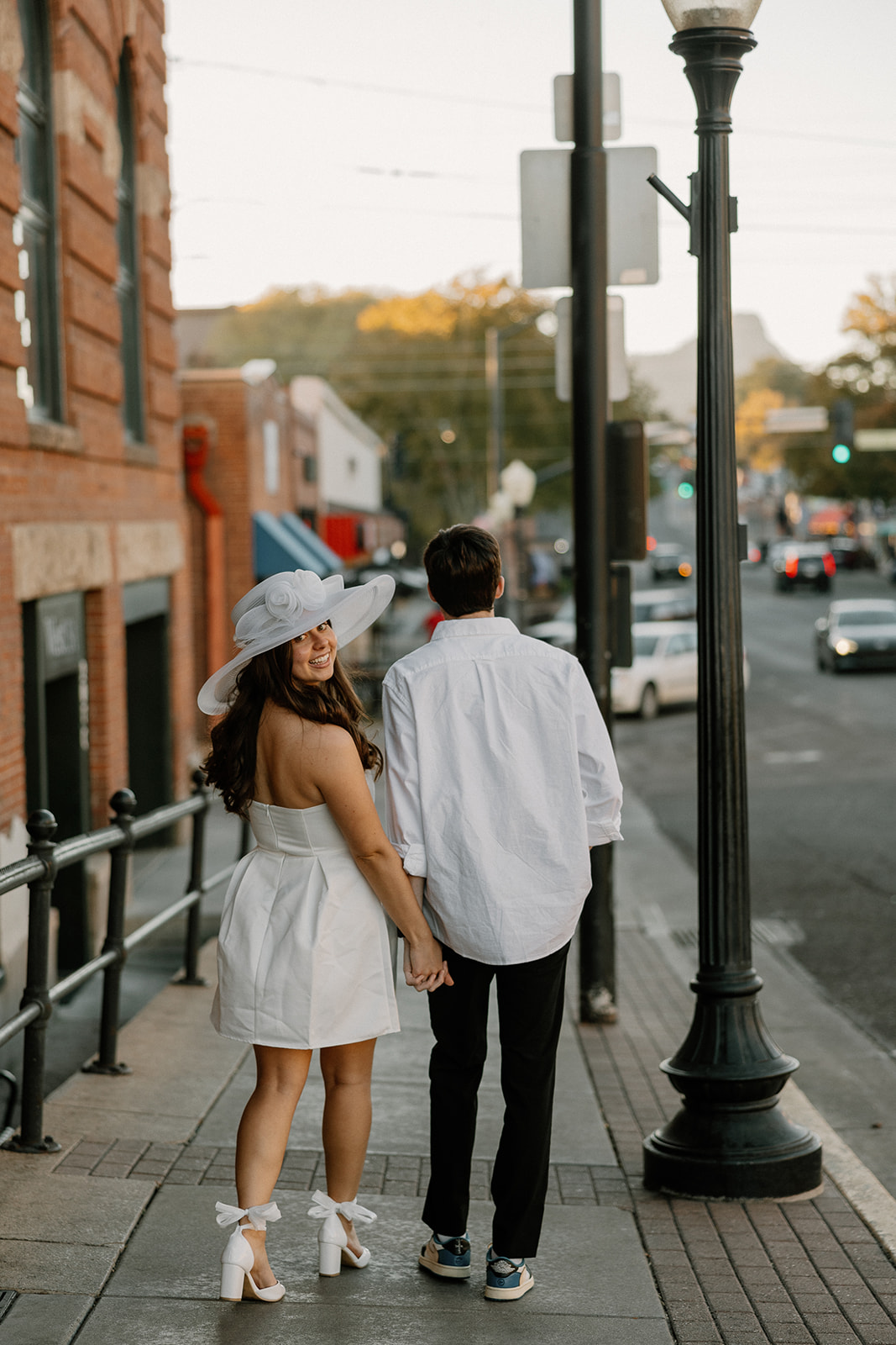 couple walking in downtown prescott during photoshoot in a white dress and white collard shirt