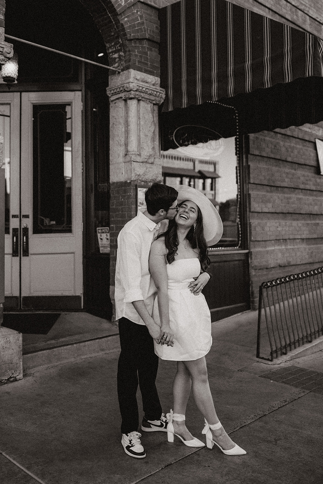 couple walking in downtown prescott during photoshoot in a white dress and white collard shirt