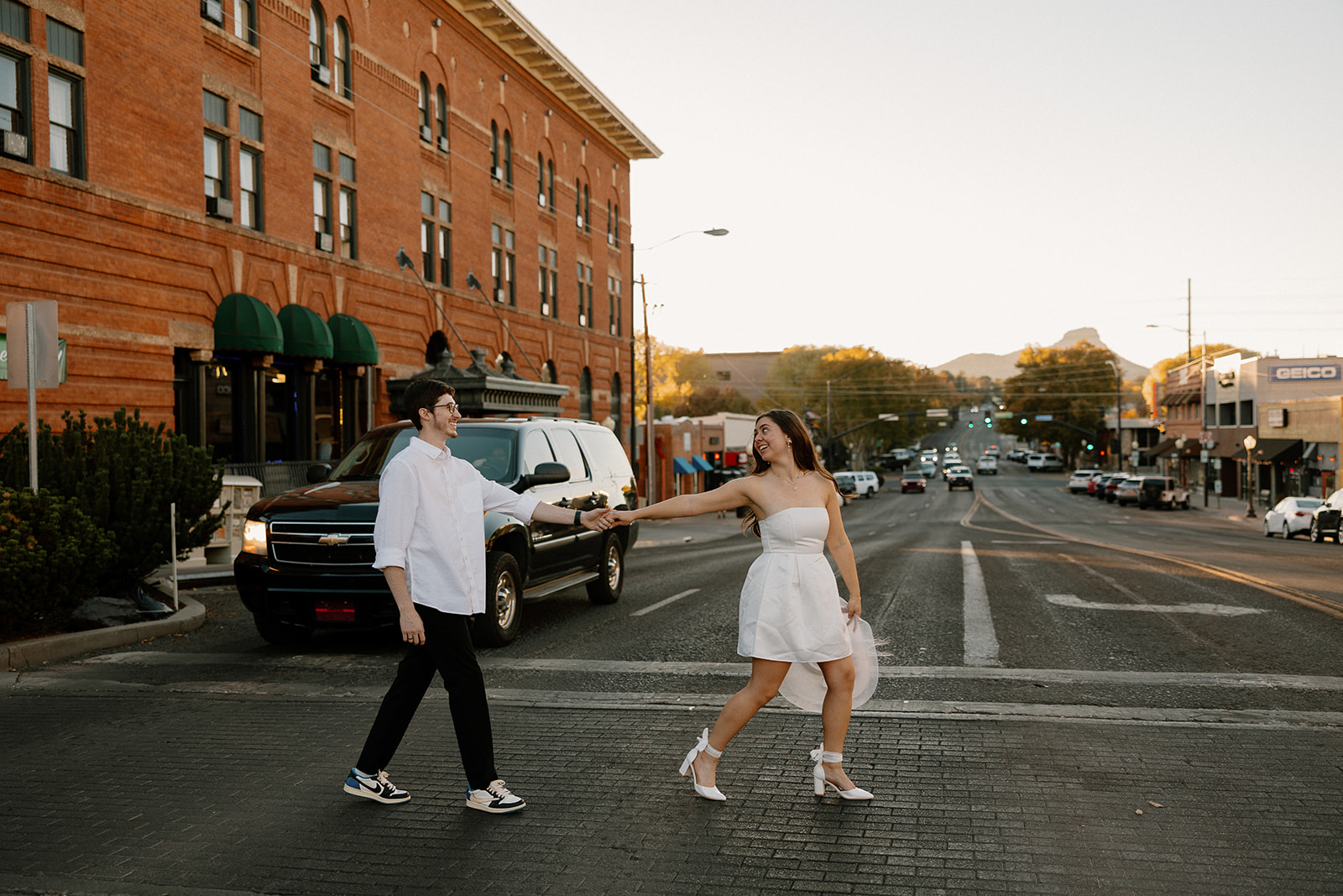 couple walking in downtown prescott during photoshoot in a white dress and white collard shirt