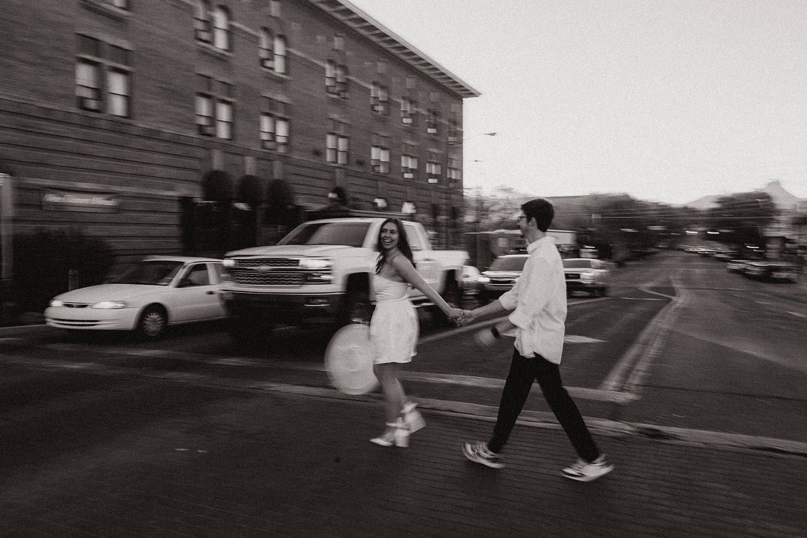 couple walking in downtown prescott during photoshoot in a white dress and white collared shirt