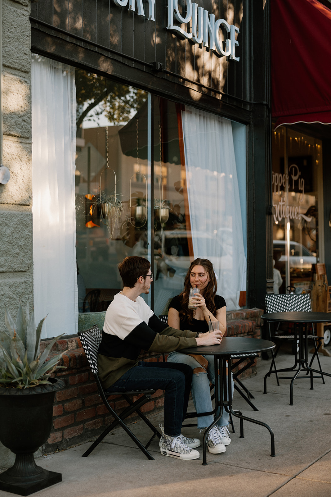 couple sips iced coffee outside of downtown prescott az on a black table and aztec bench