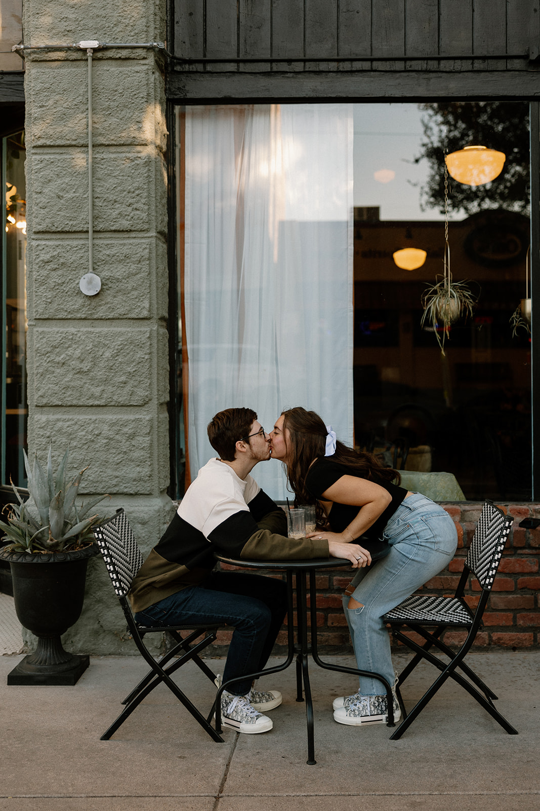 couple sips iced coffee outside of downtown prescott az on a black table and aztec bench