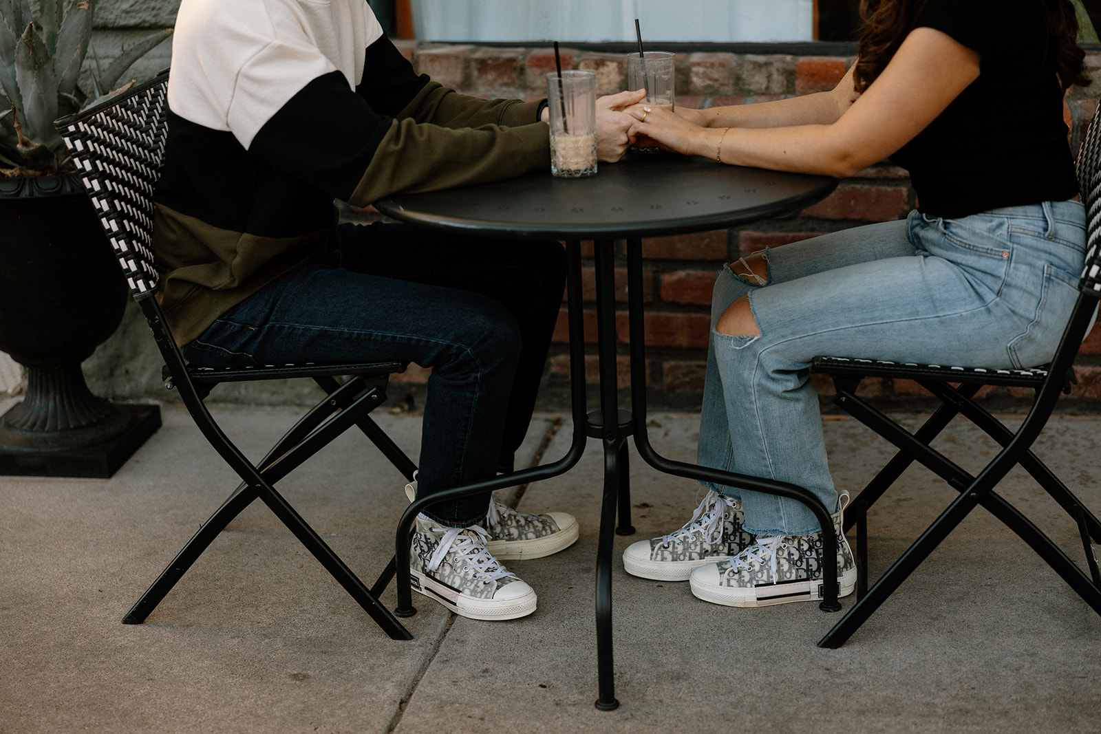 couple sips iced coffee outside of downtown prescott az on a black table and aztec bench