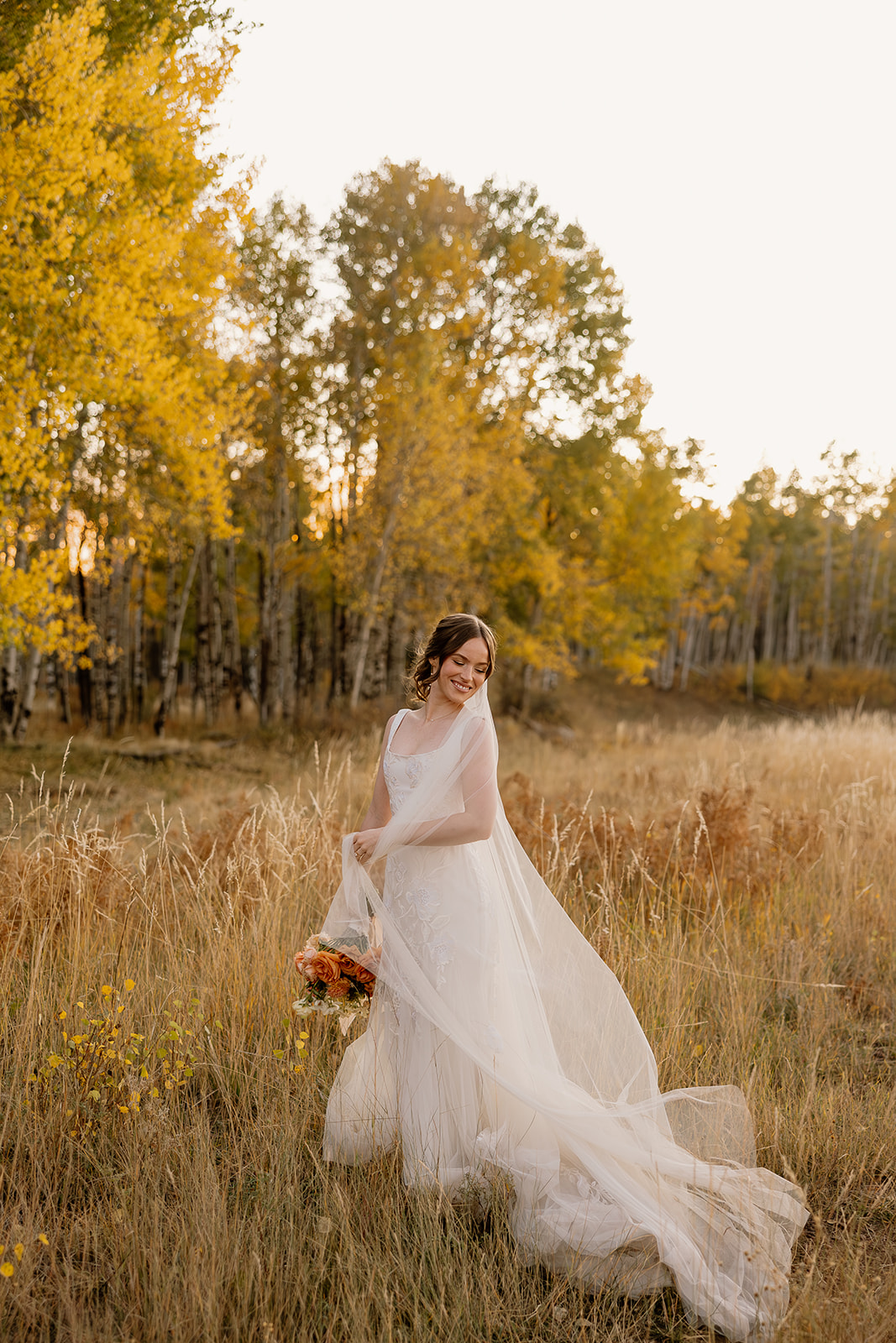 bride poses for a photo in an Arizona field after her Fall wedding in Flagstaff