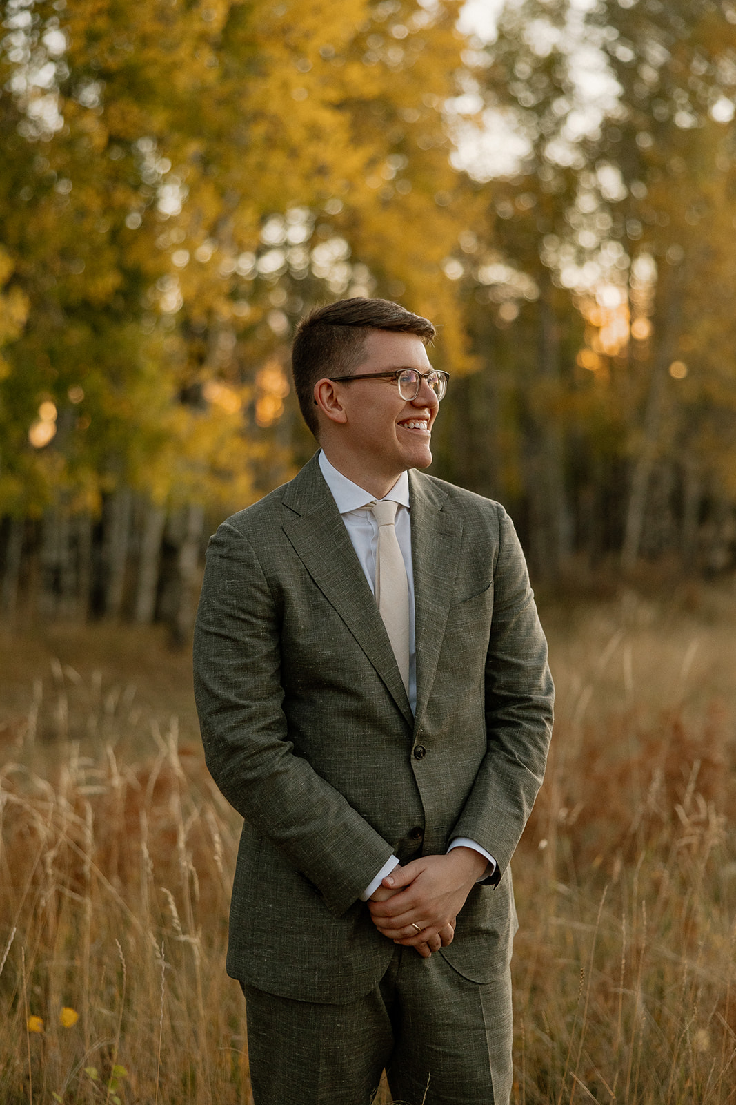 groom poses for a photo in an Arizona field after his Fall wedding in Flagstaff