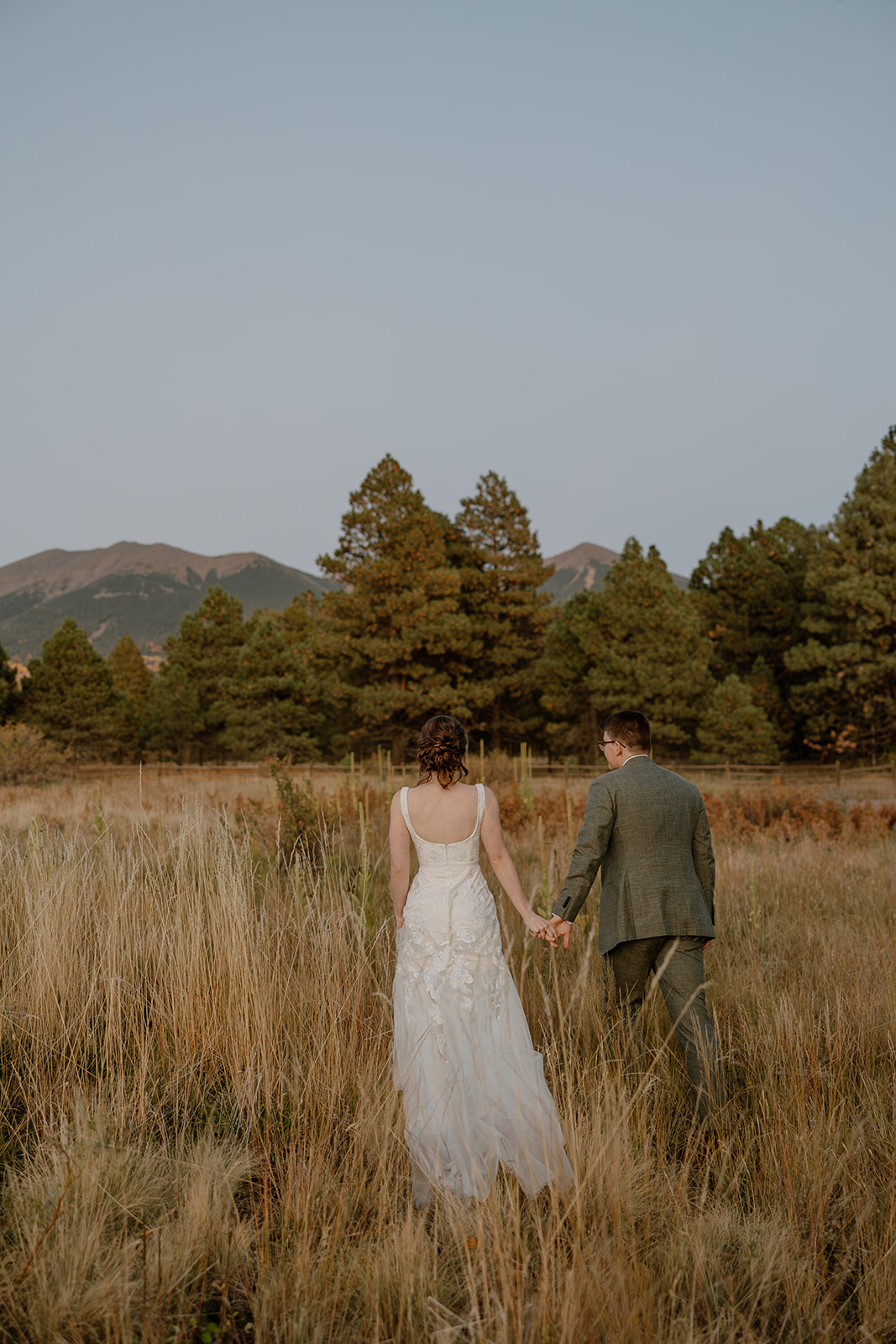 bride and groom stroll through a Arizona field together after their Arizona wedding day