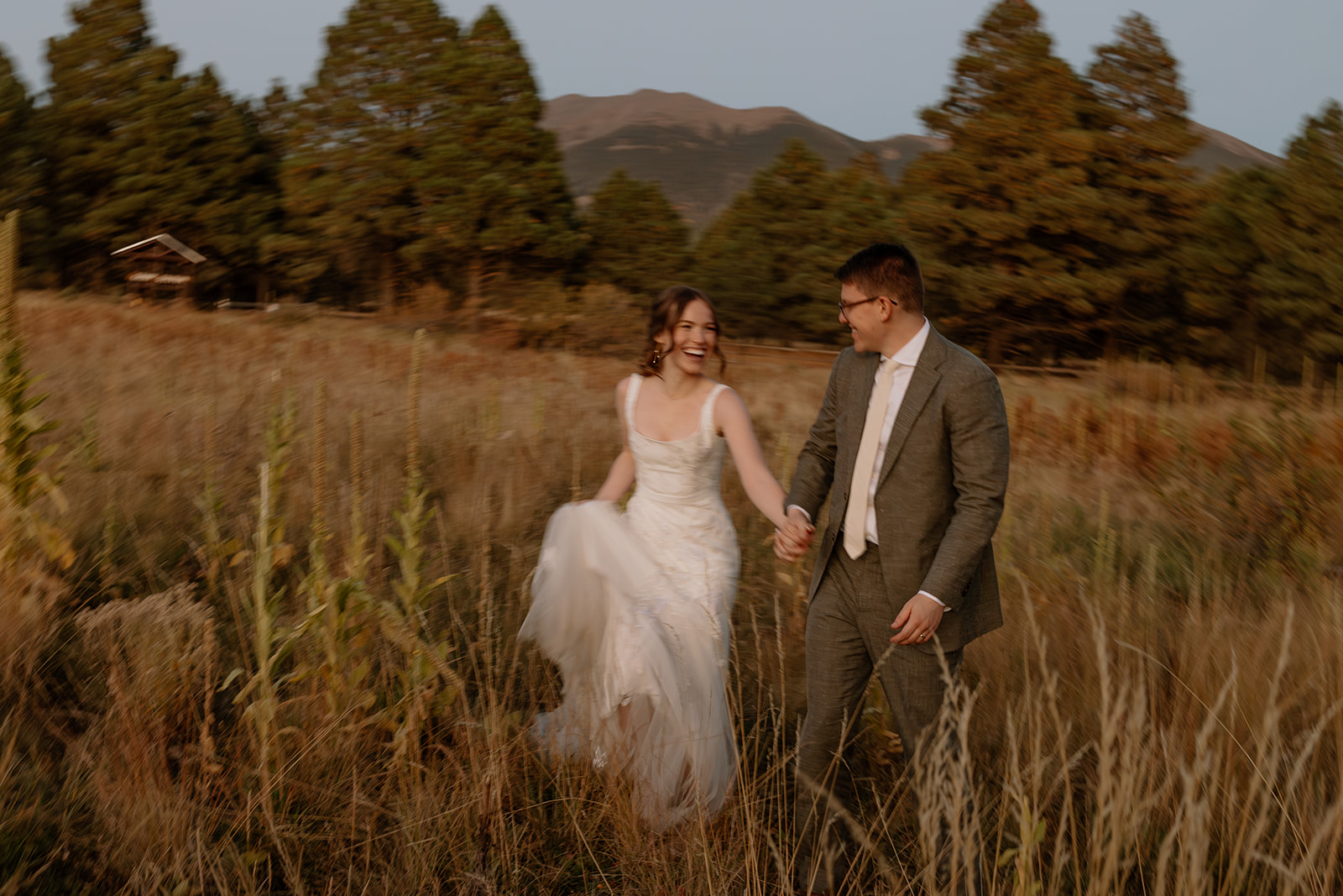 bride and groom stroll through a Arizona field together after their Arizona wedding day