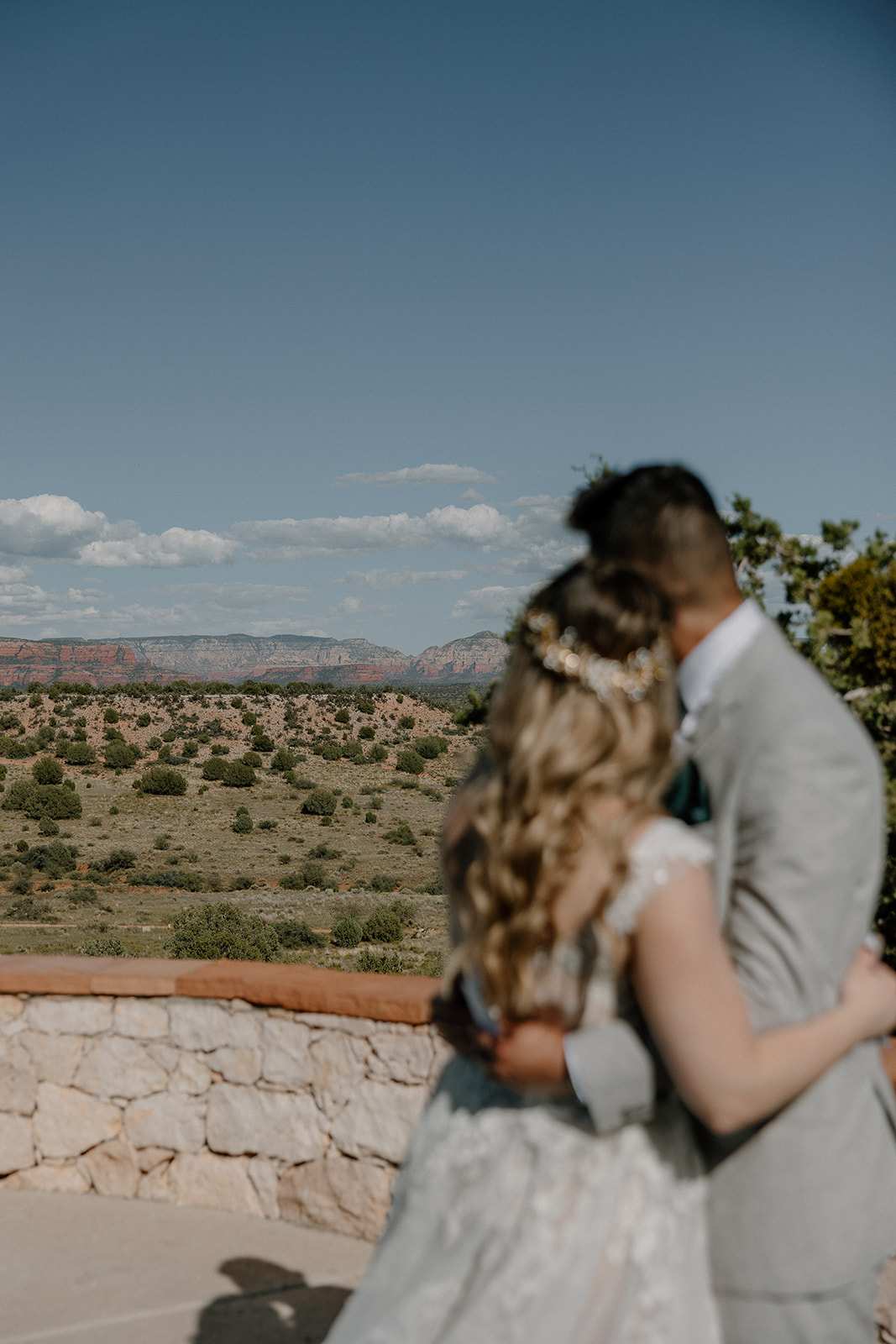 Couple hugs while looking at view from ceremony site at The Sanctuary at Sacred Mesa