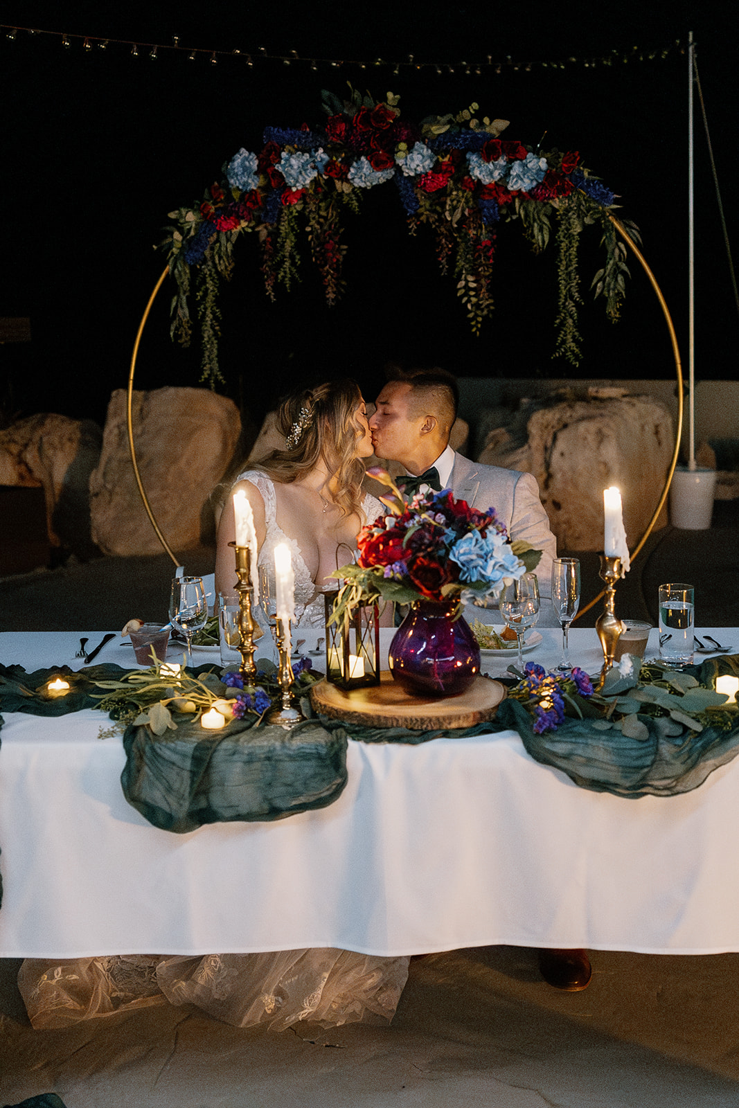 Candlelit dinner with bride and groom sitting at table together kissing