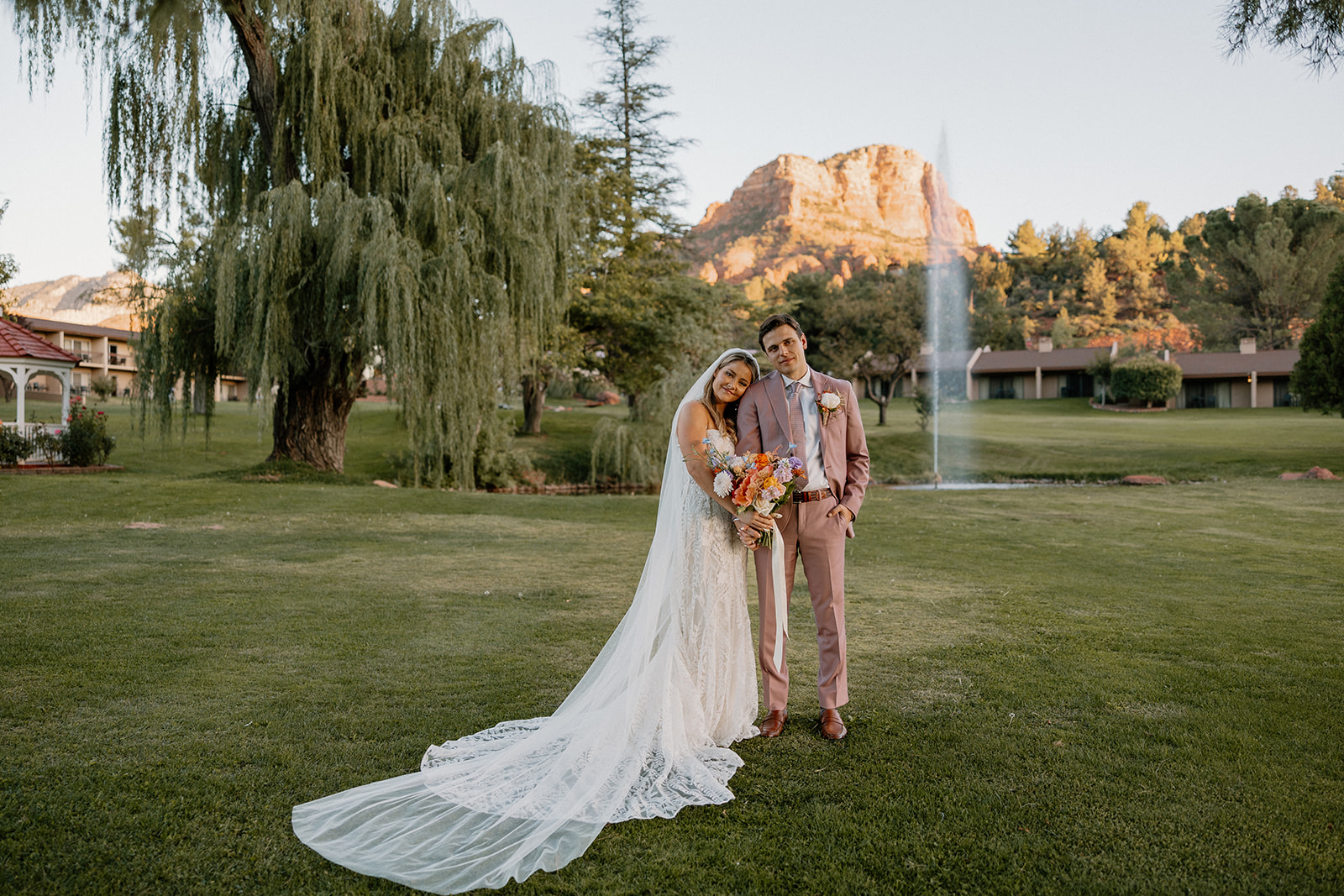 Bride and groom leaning heads against one another while holding hands
