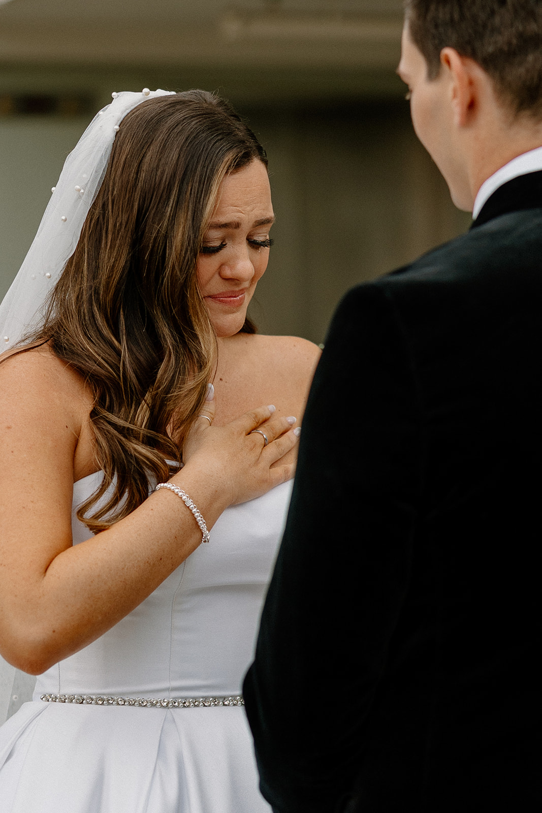 bride with hand on heart while getting emotional reading vows to groom