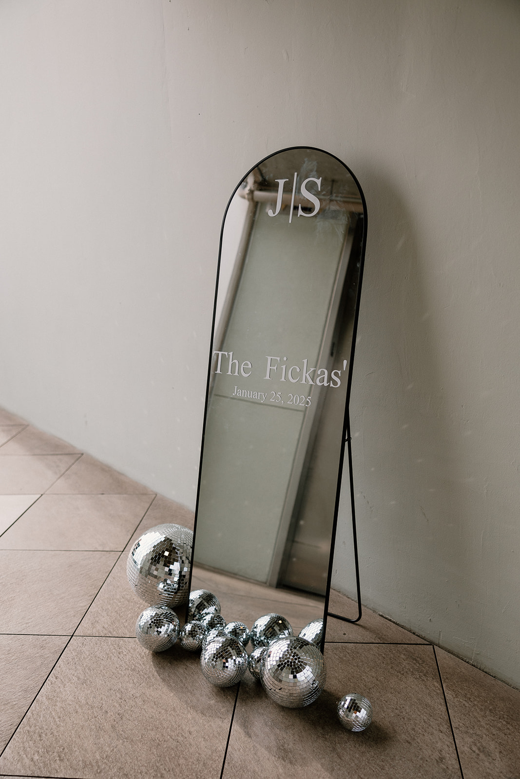 tall mirror with couple's married last name with disco balls on the ground around it