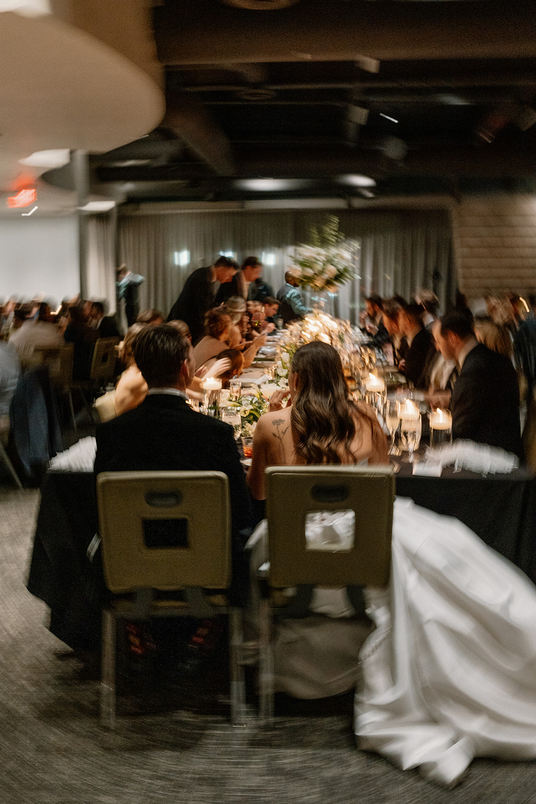 bride and groom at reception with wedding guests eating dinner