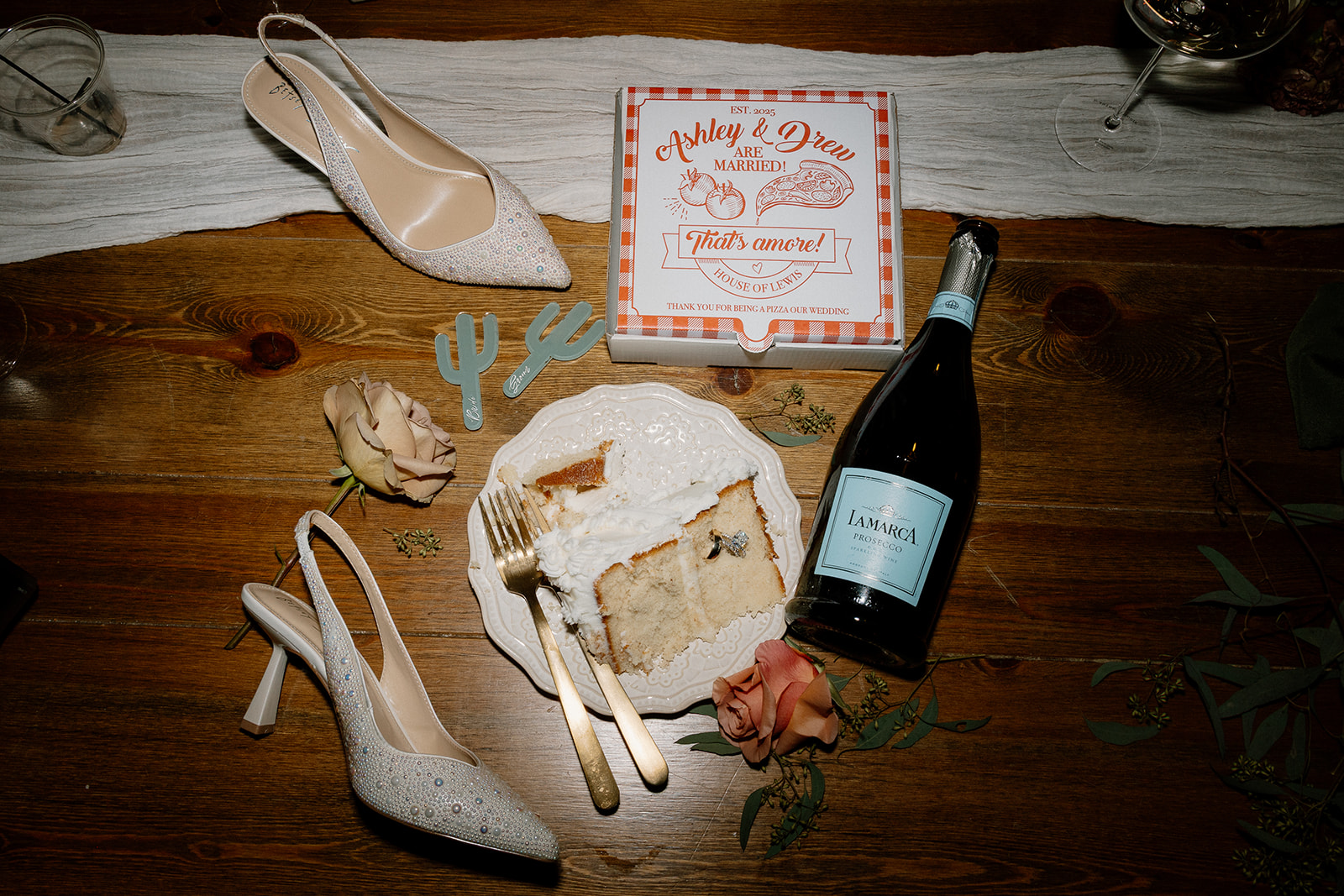 brides heels, champagne, and a slice of wedding cake lay in flatlay detail photo