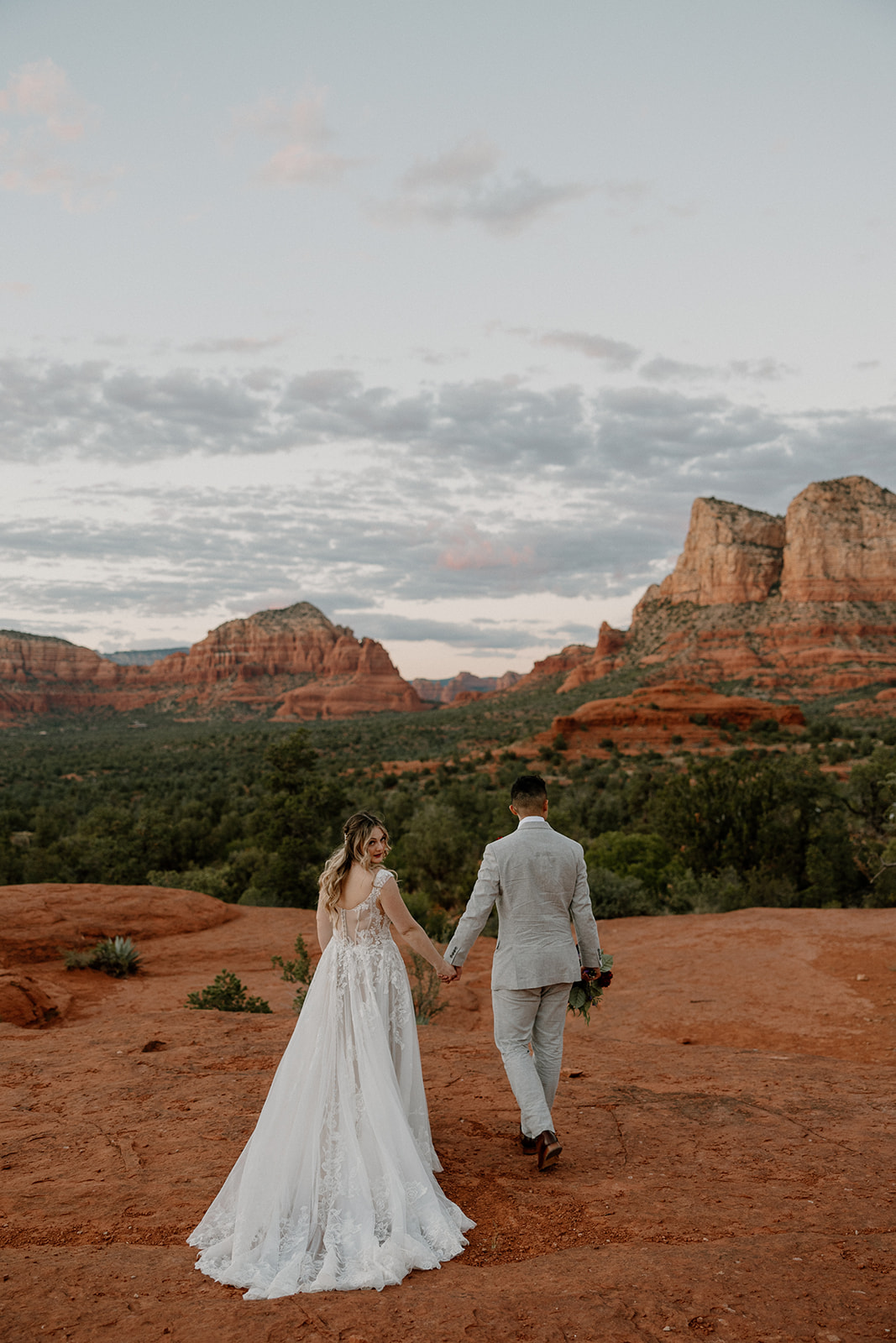 Couple walking hand in hand towards red rocks after intimate wedding 
