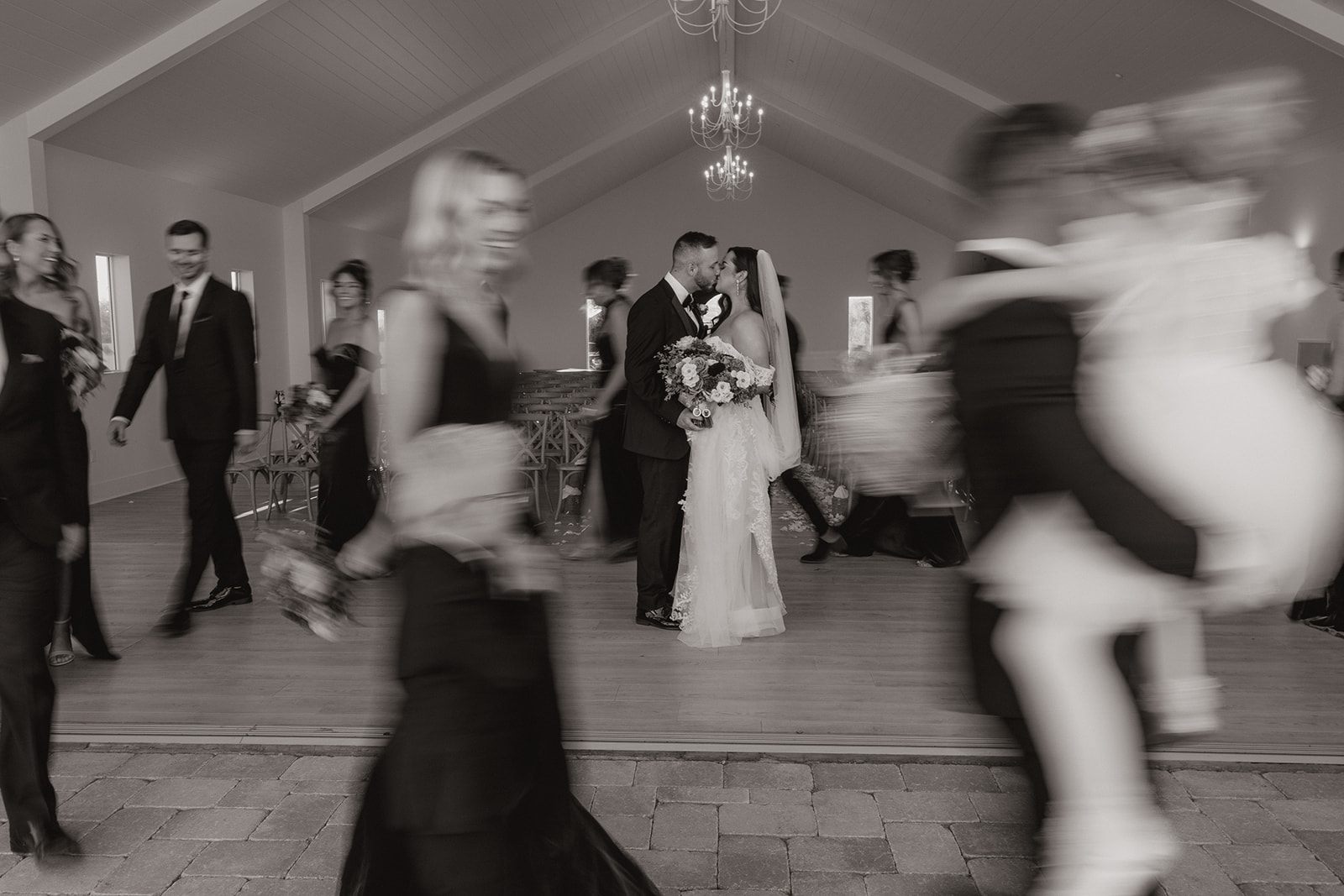 bride and groom share a kiss as their guests walk around them in a cinematic style