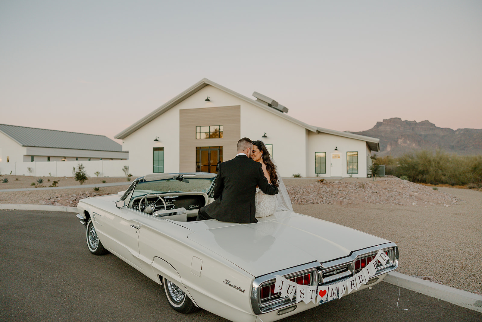 bride and groom pose in a vintage convertible 