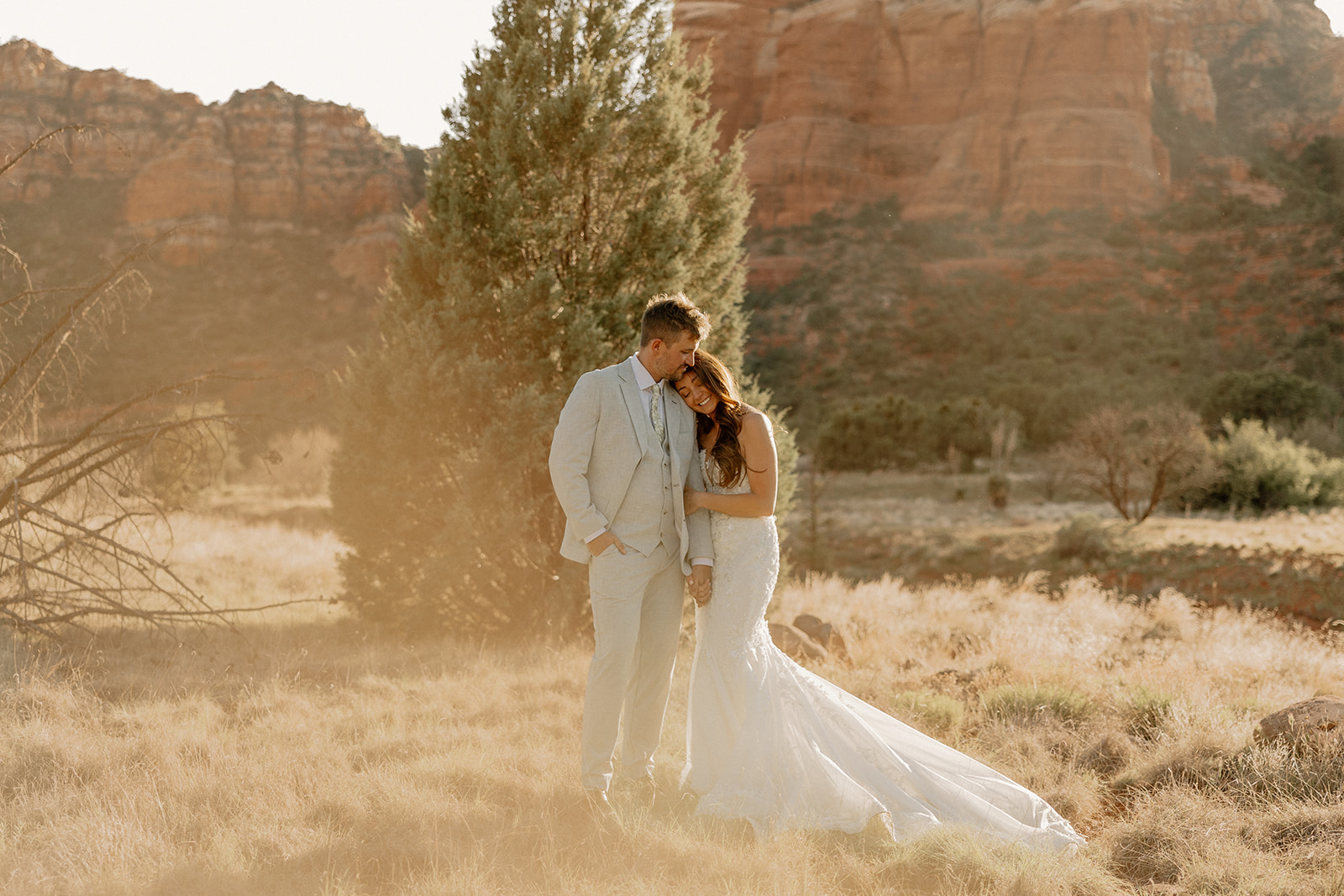 Golden hour couple portraits after wedding with bride leaning on groom and embracing