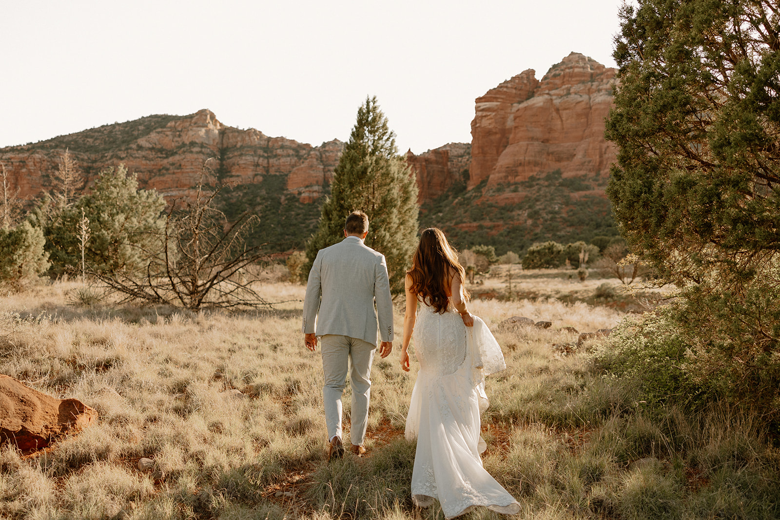 Couple walking through grassy area during golden hour
