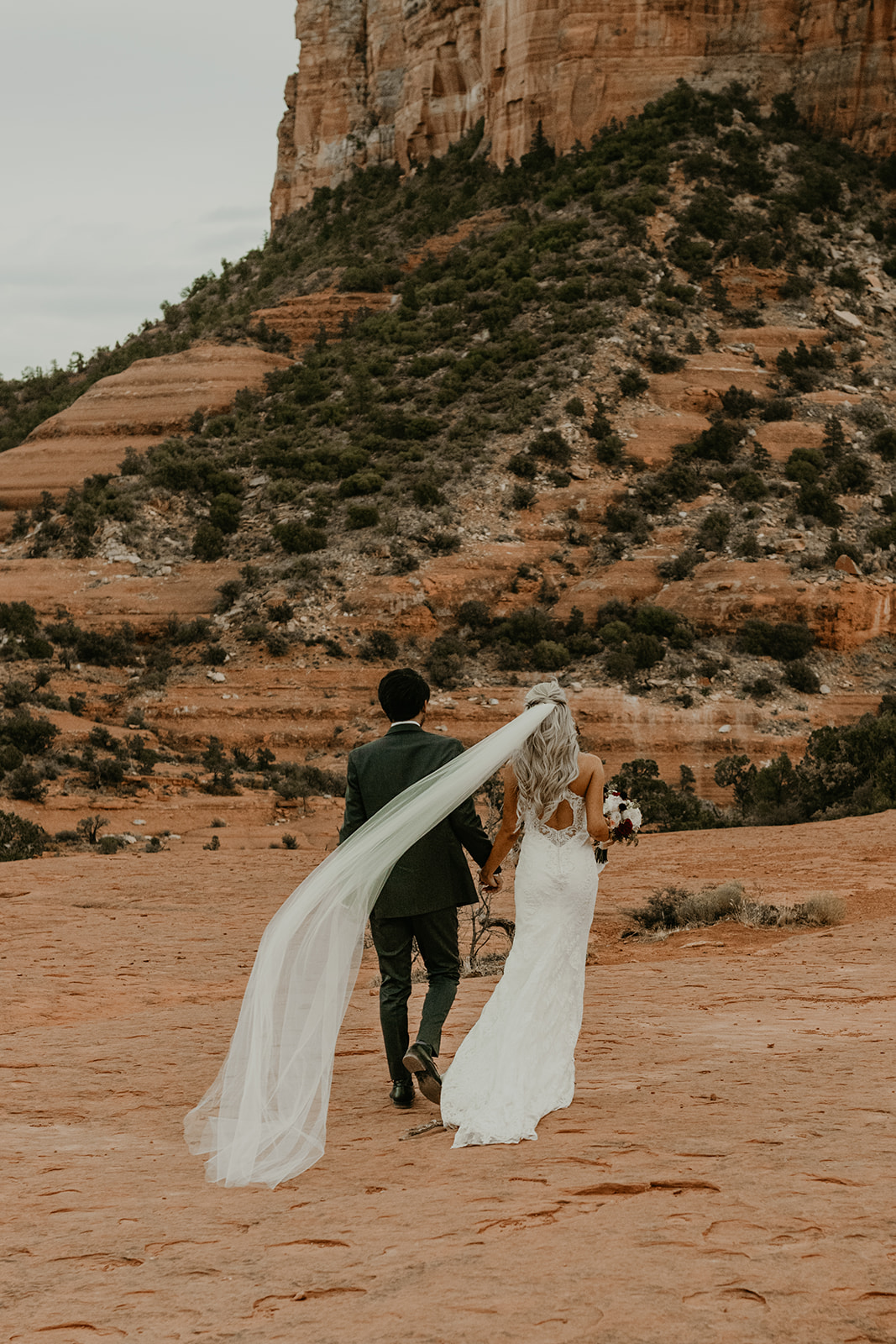 couple walking towards the red rocks during outdoor bridal portraits